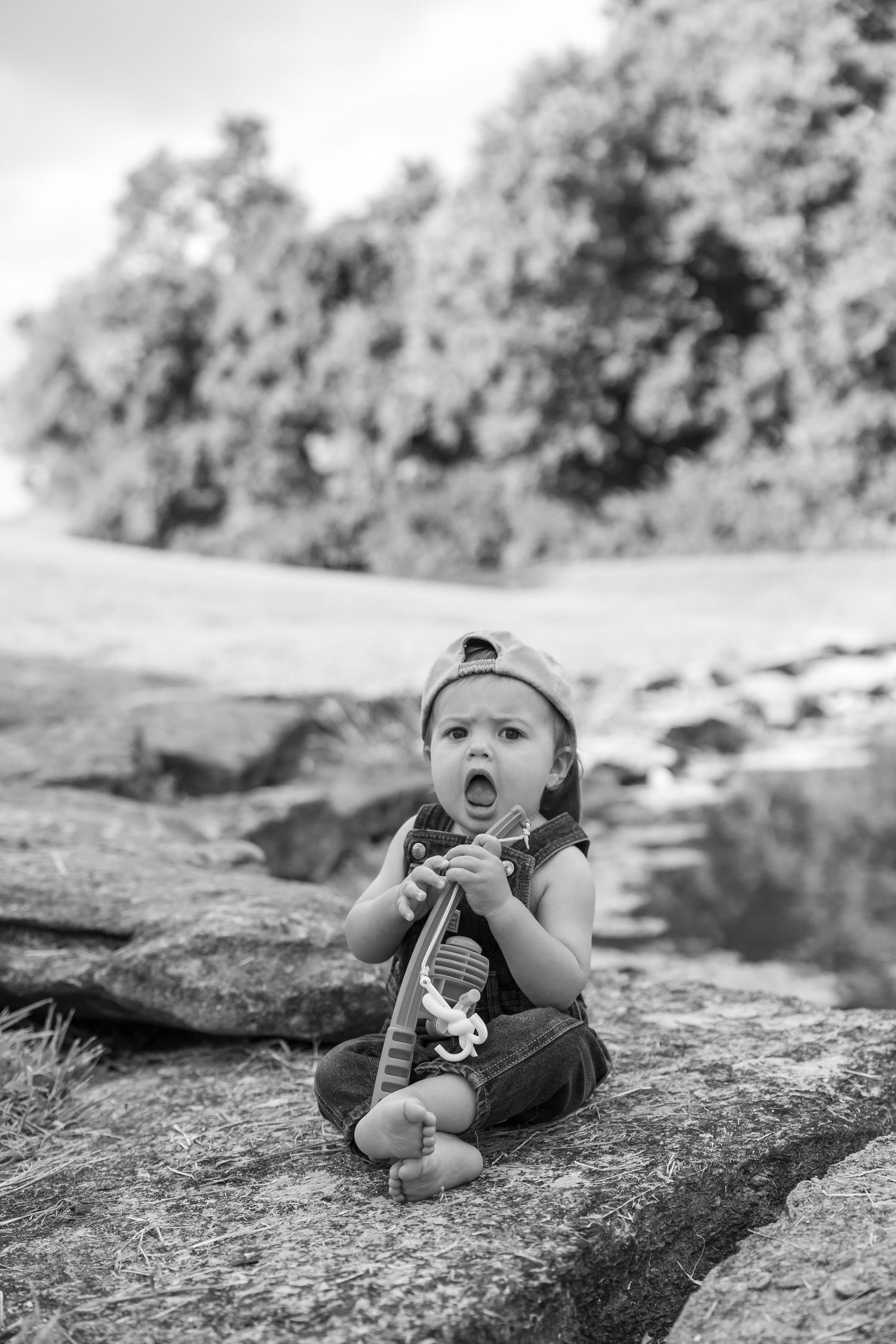 Baby in casual wear lying on rocky surface in black and white photography.