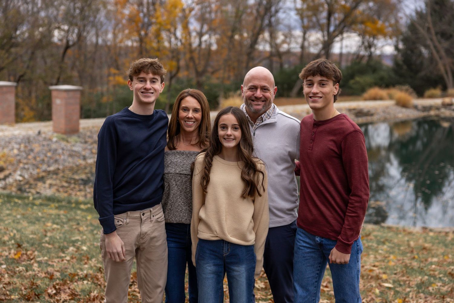 Family portrait of four people wearing coordinated fall colors outdoors.