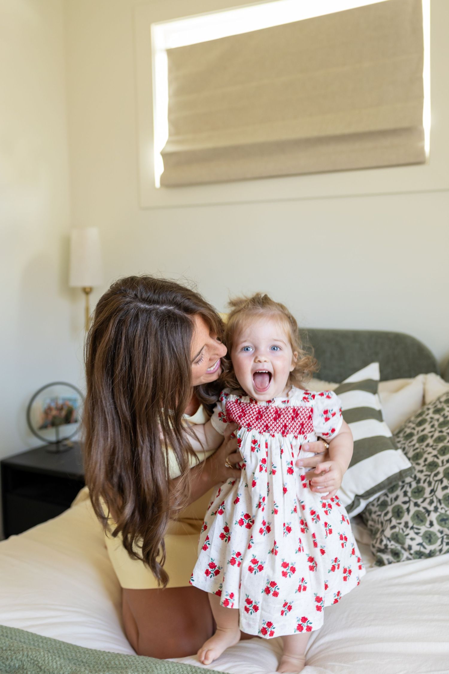 Tender moment shared on white bedding in bright, sunlit bedroom.