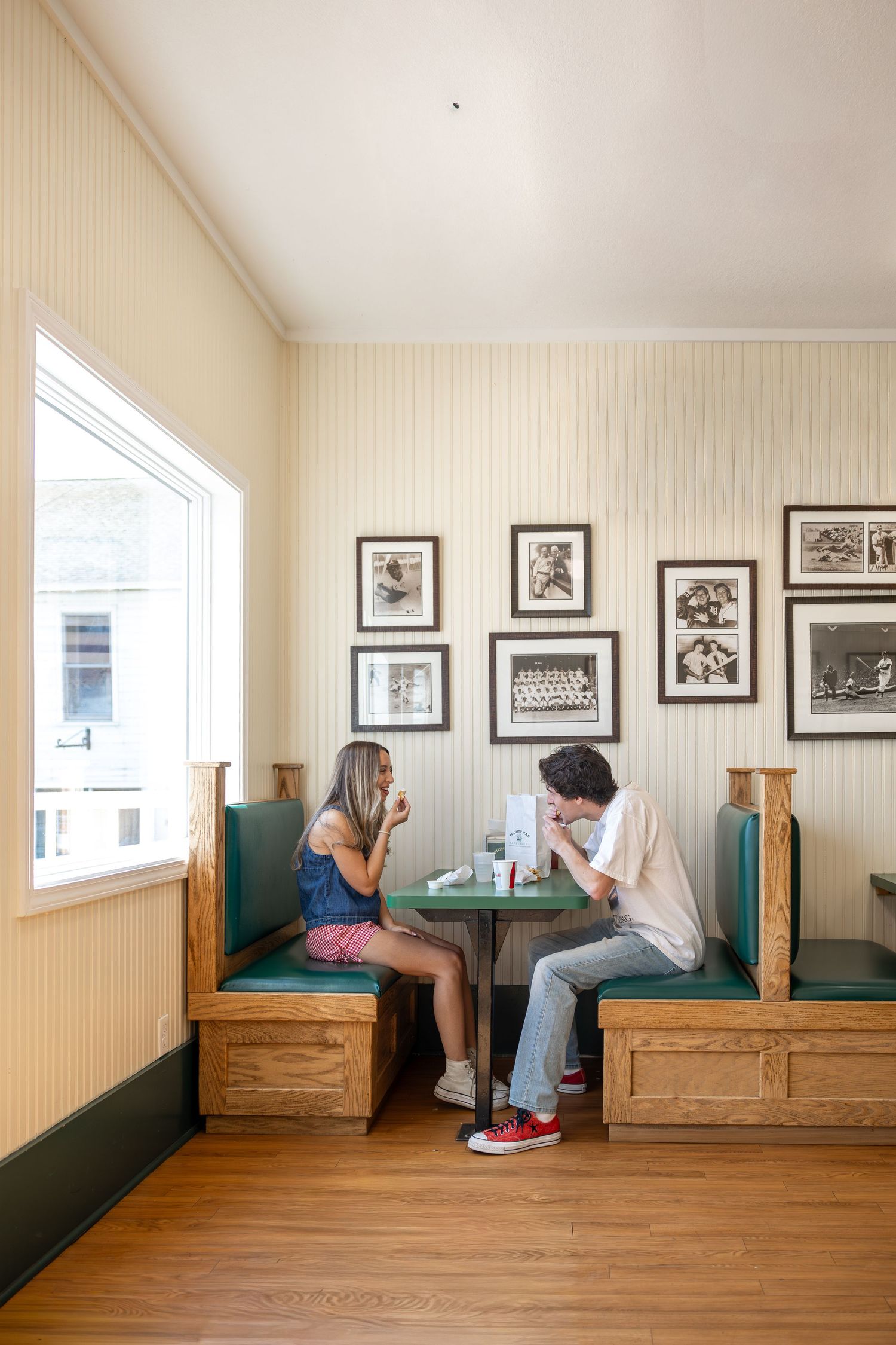 Interior room with wooden benches and black and white framed photos on beige walls.