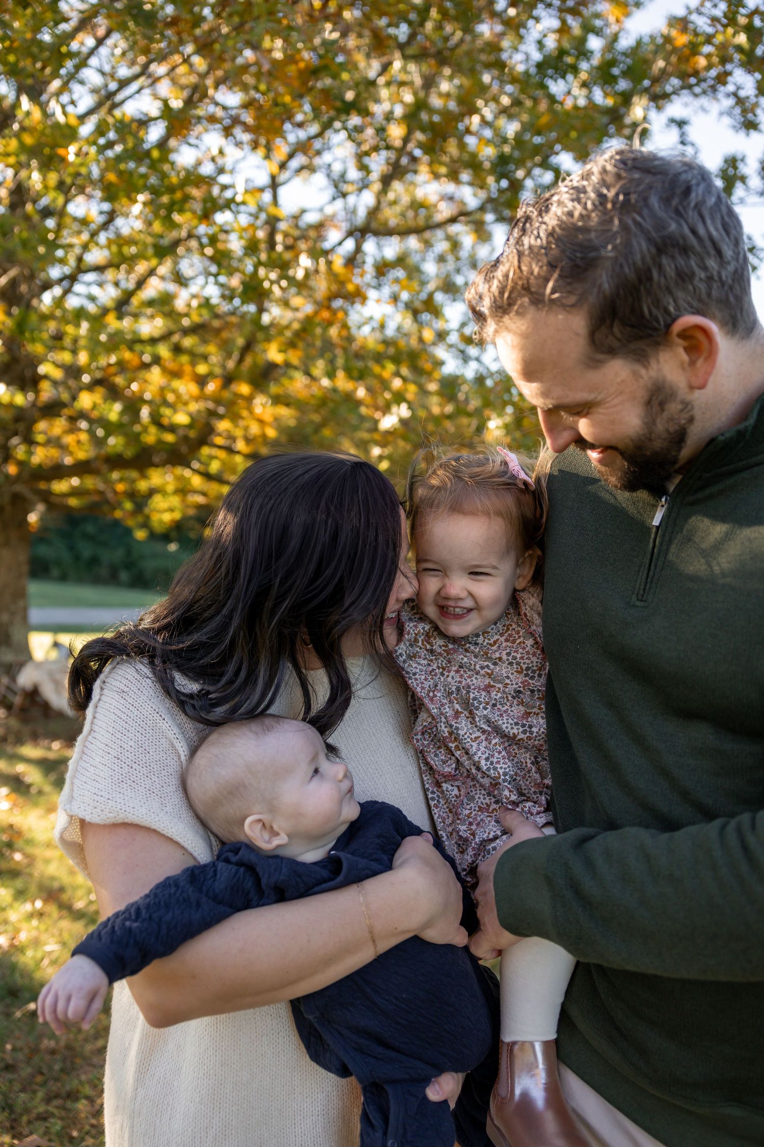 Family shares tender hugs and embraces outdoors during a warm autumn day.