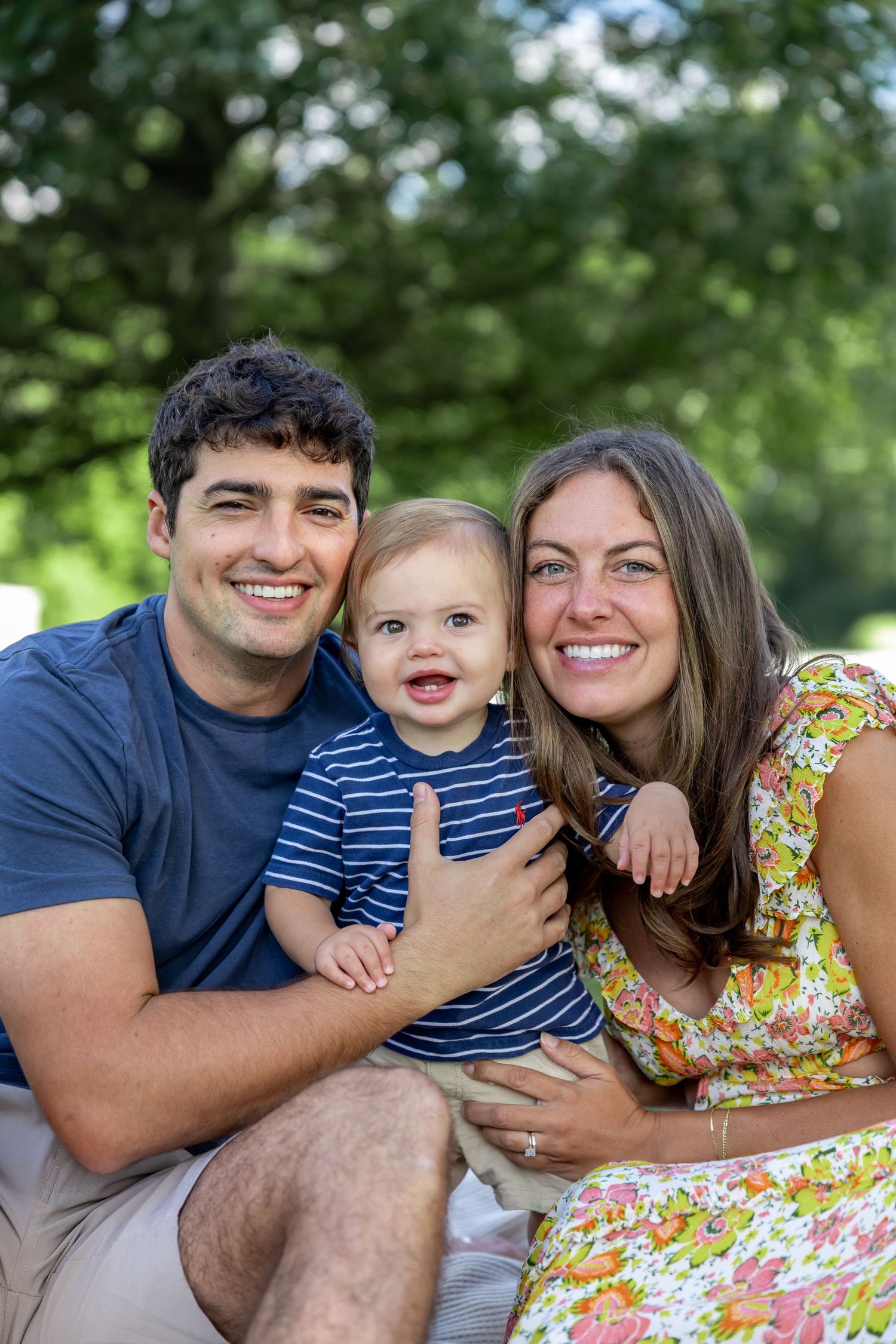 Family portrait session outdoors with vibrant greenery in the background.