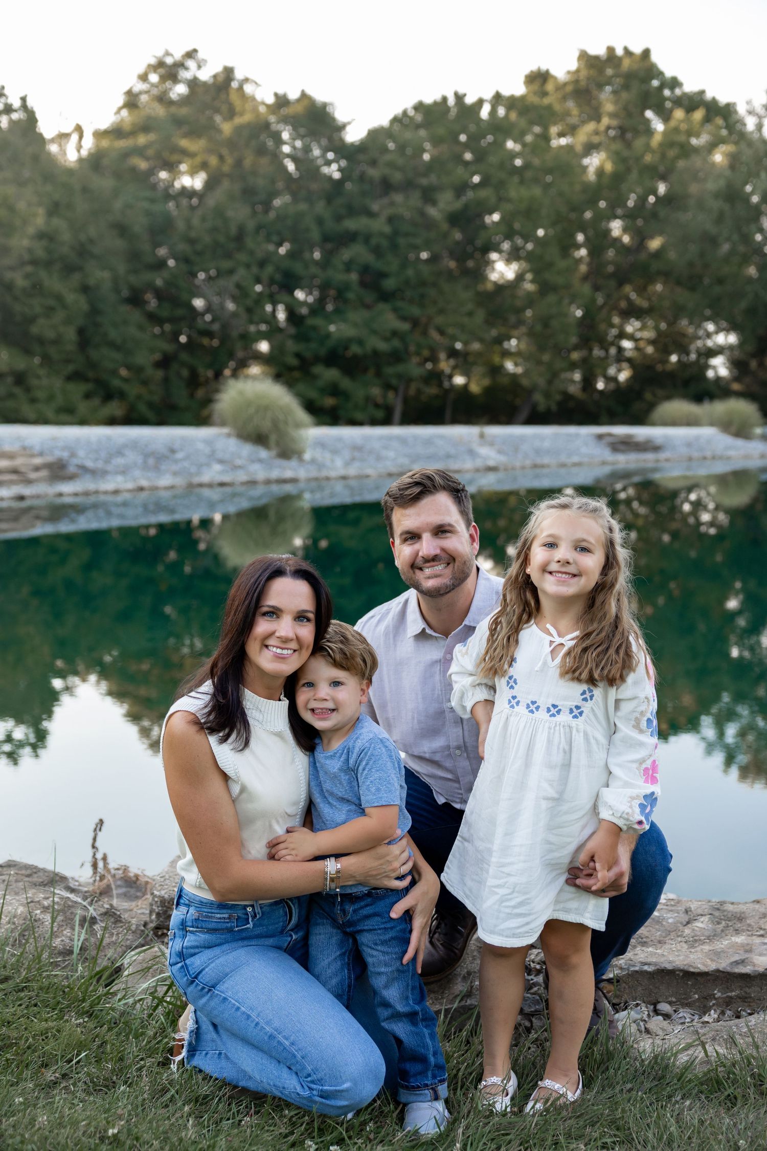 Family sitting by a lake at sunset for casual outdoor portraits.