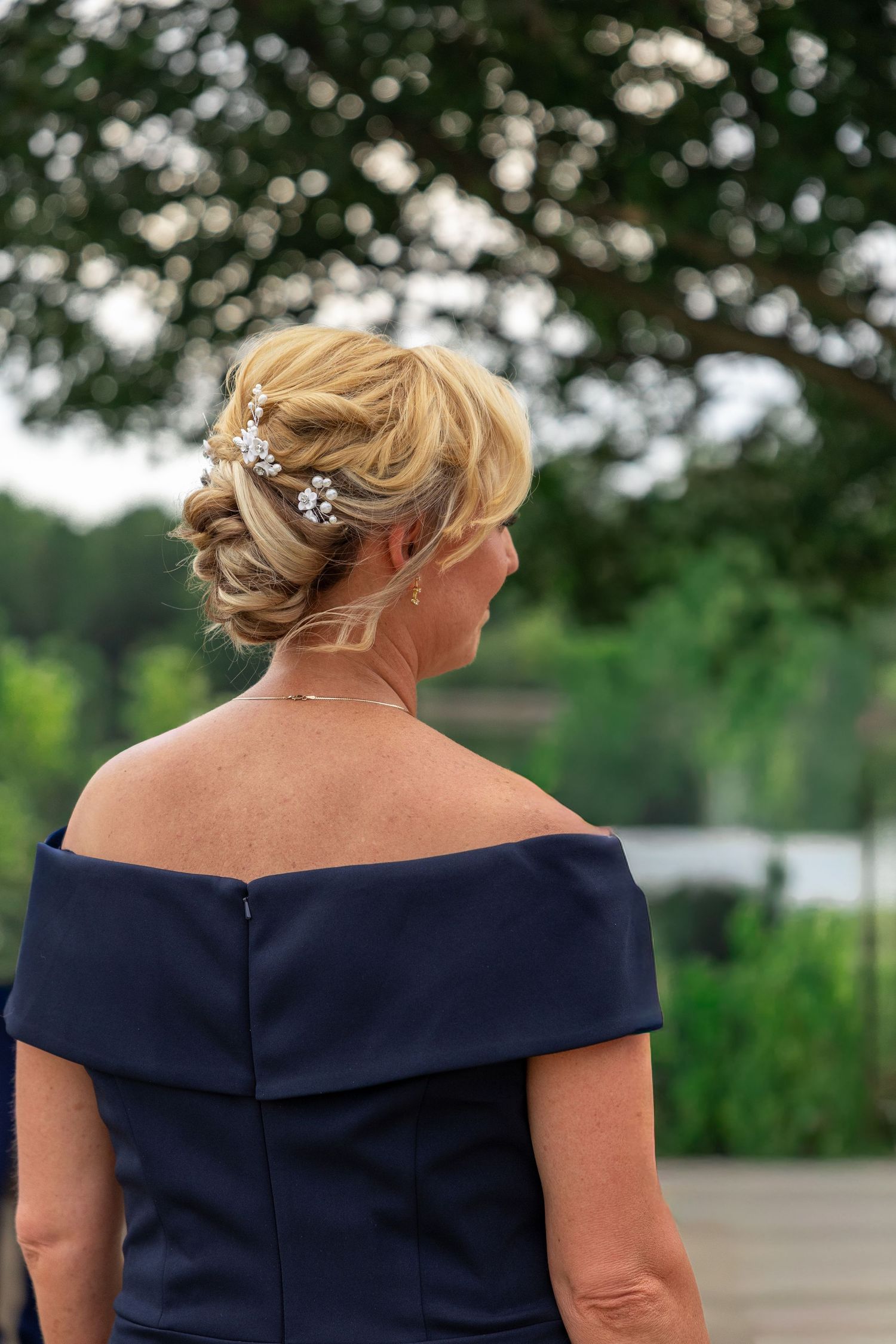 Back view of navy blue formal dress with off-shoulder neckline and elegant updo hairstyle.