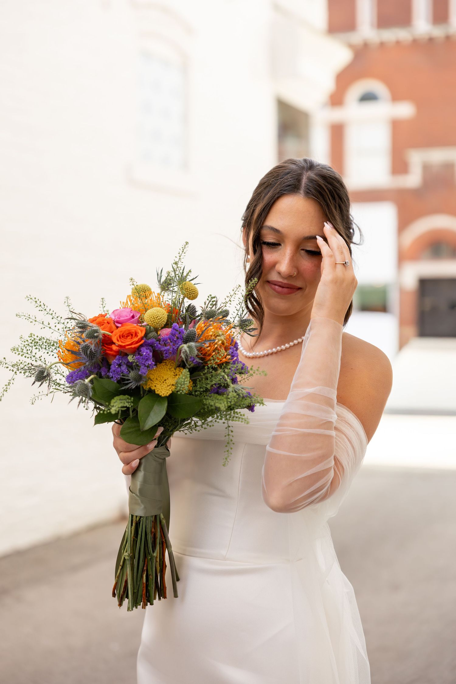 Colorful wildflower wedding bouquet with bright orange, purple and yellow blooms.