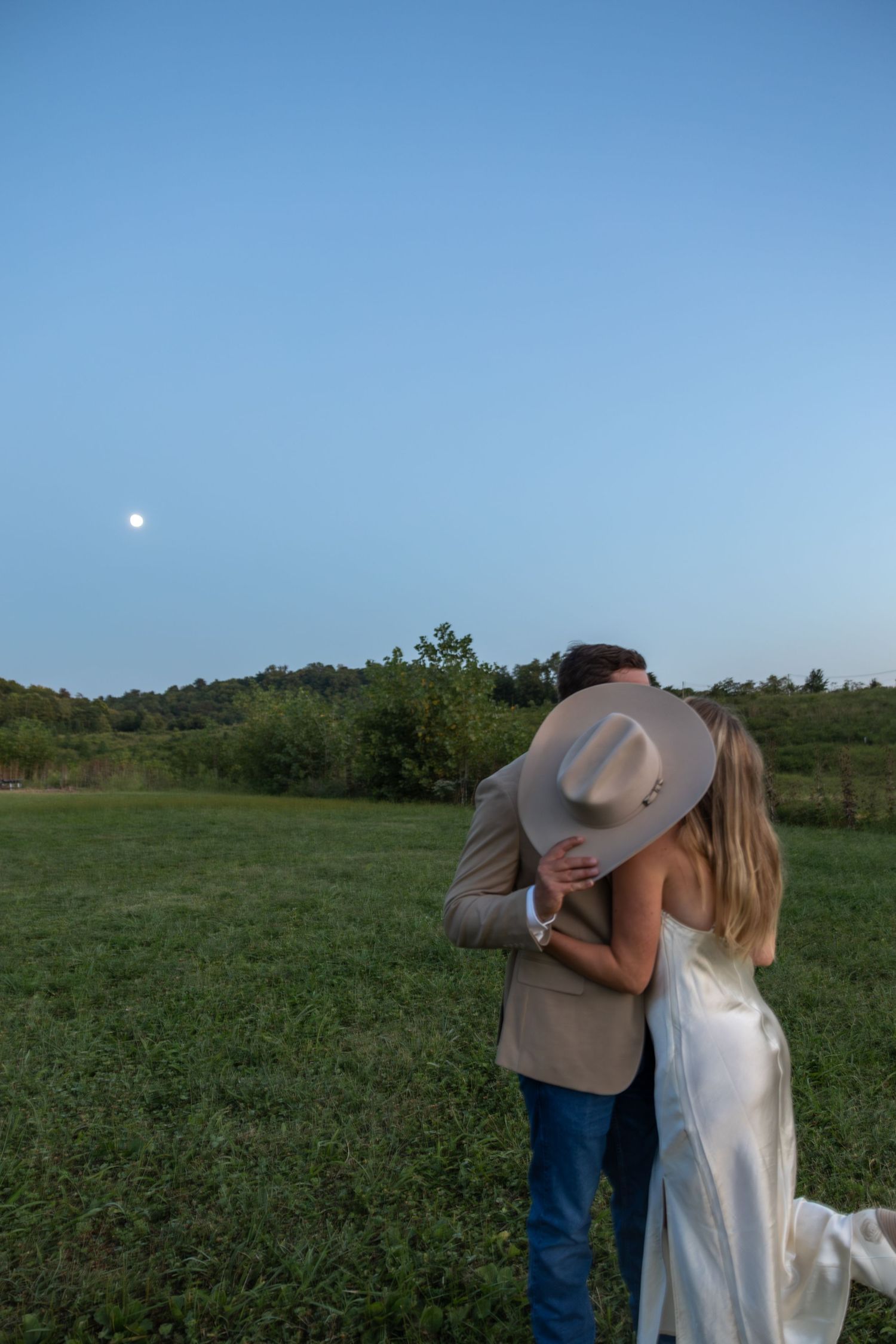 A tender moment between a couple at sunset in a rustic field setting.