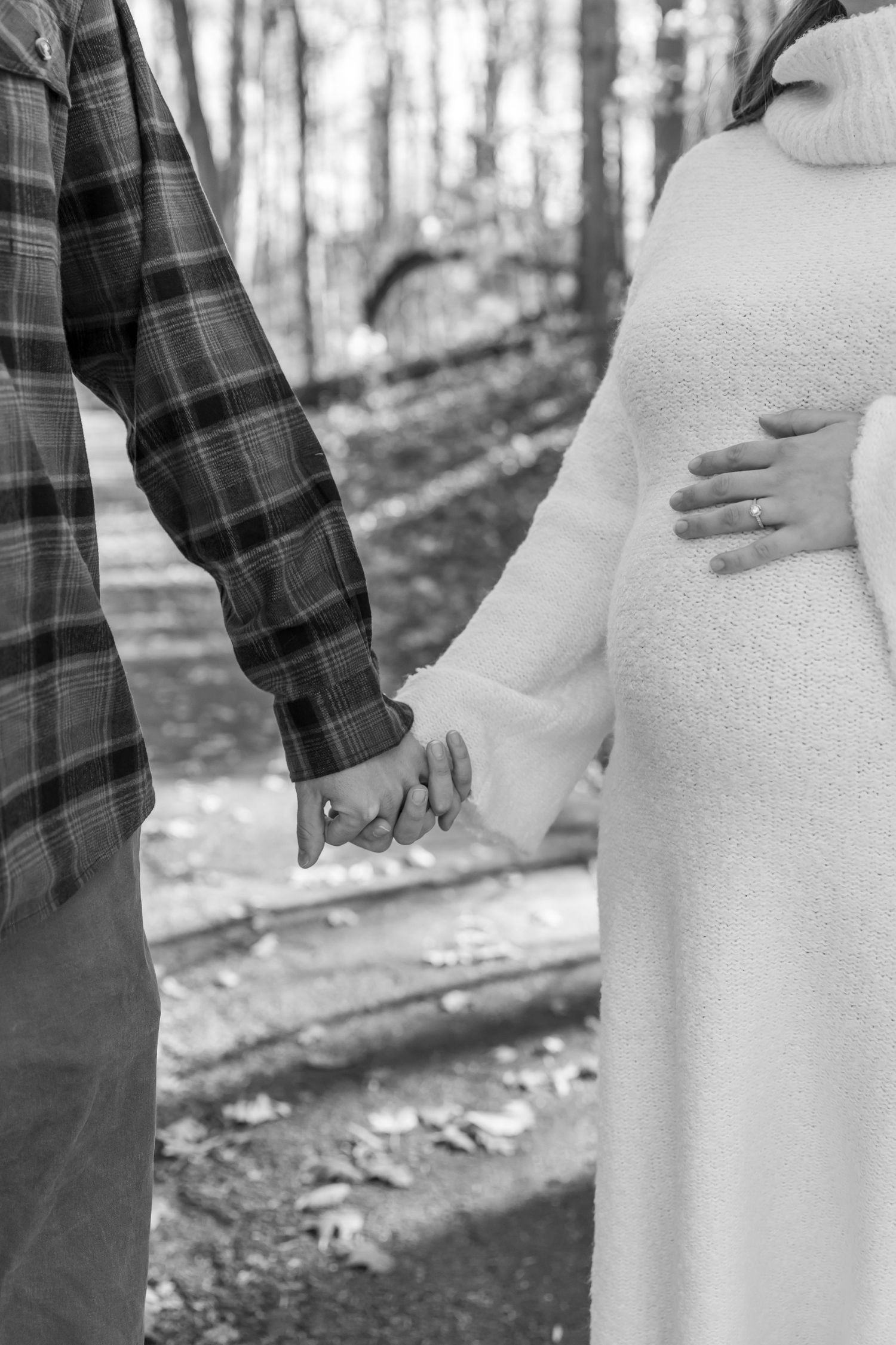 A couple poses together in a wooded area during a maternity photo shoot.