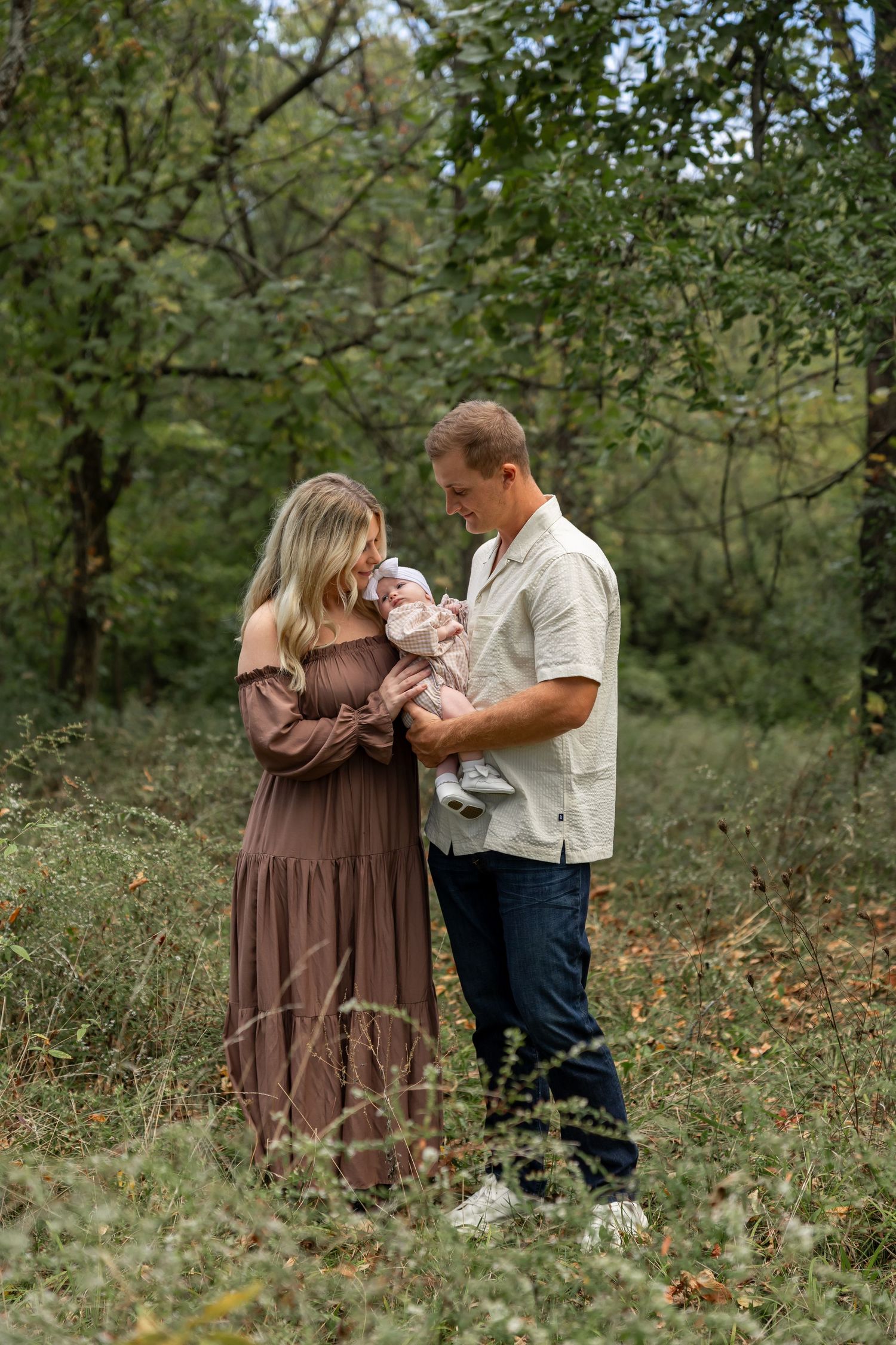 A family shares intimate moments together in a lush green natural setting.
