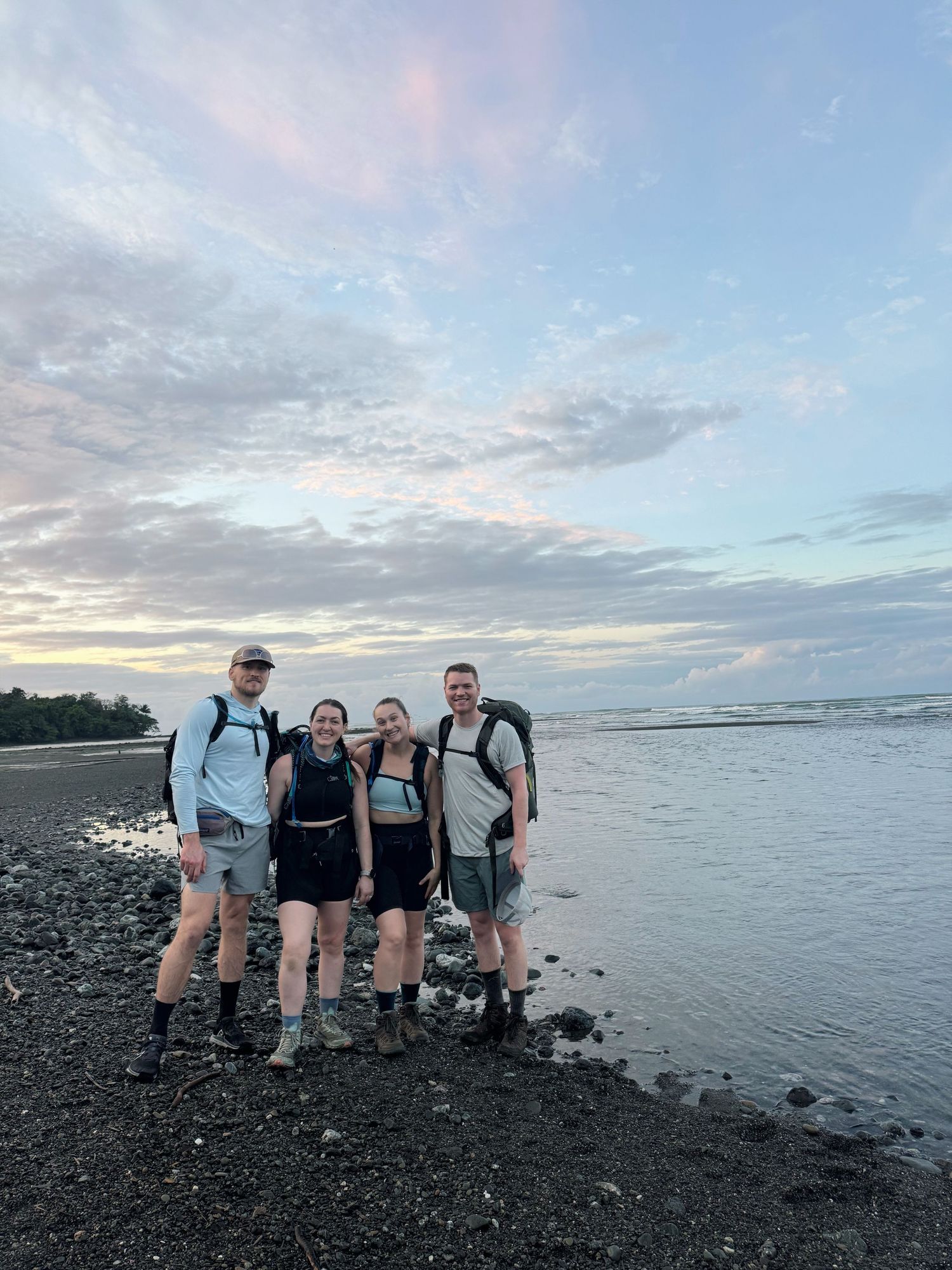 Friends in Costa Rica smiling by the ocean with sunrise in the background