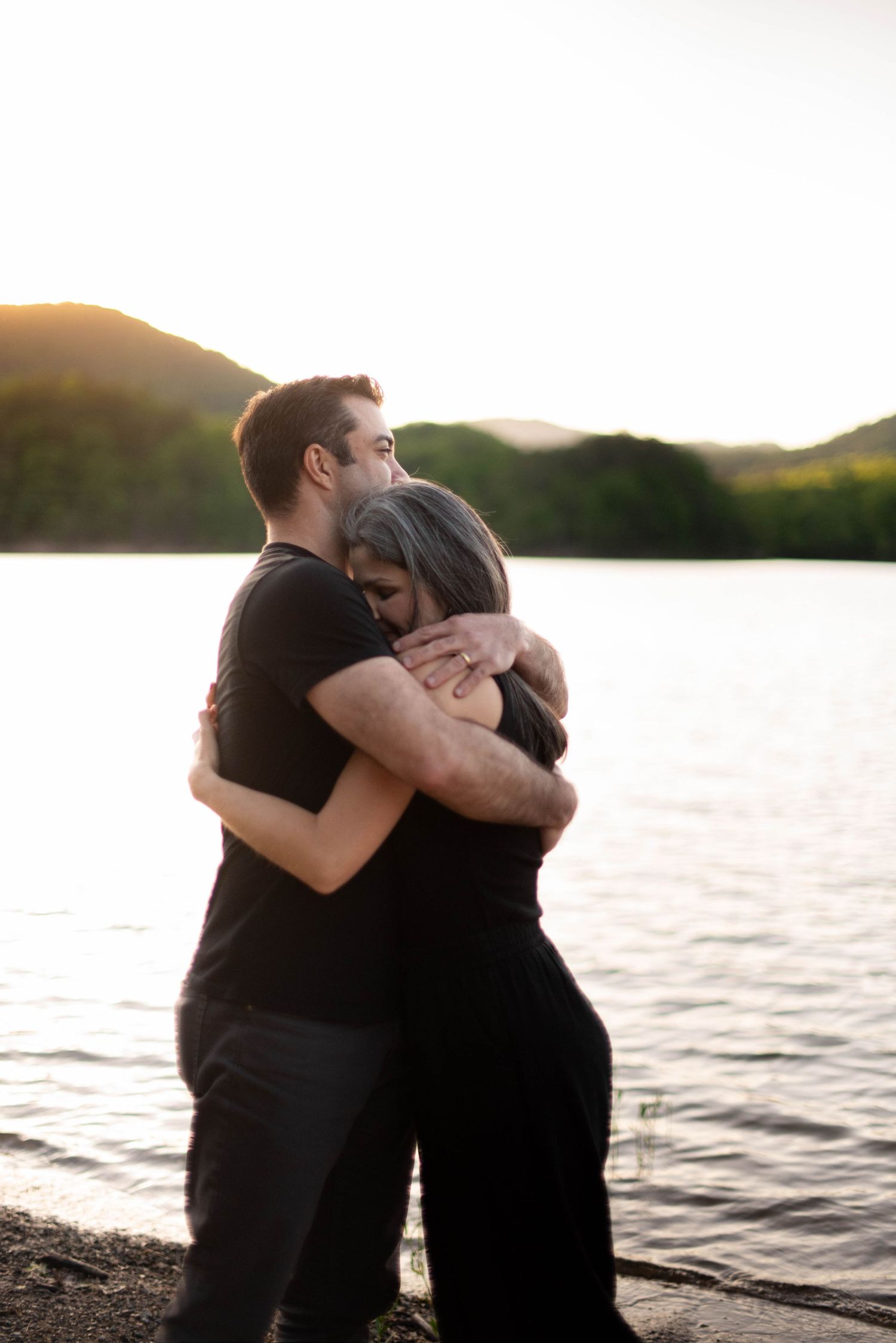 Couple hugging in front of lake in the mountains of Roanoke, VA during portrait session