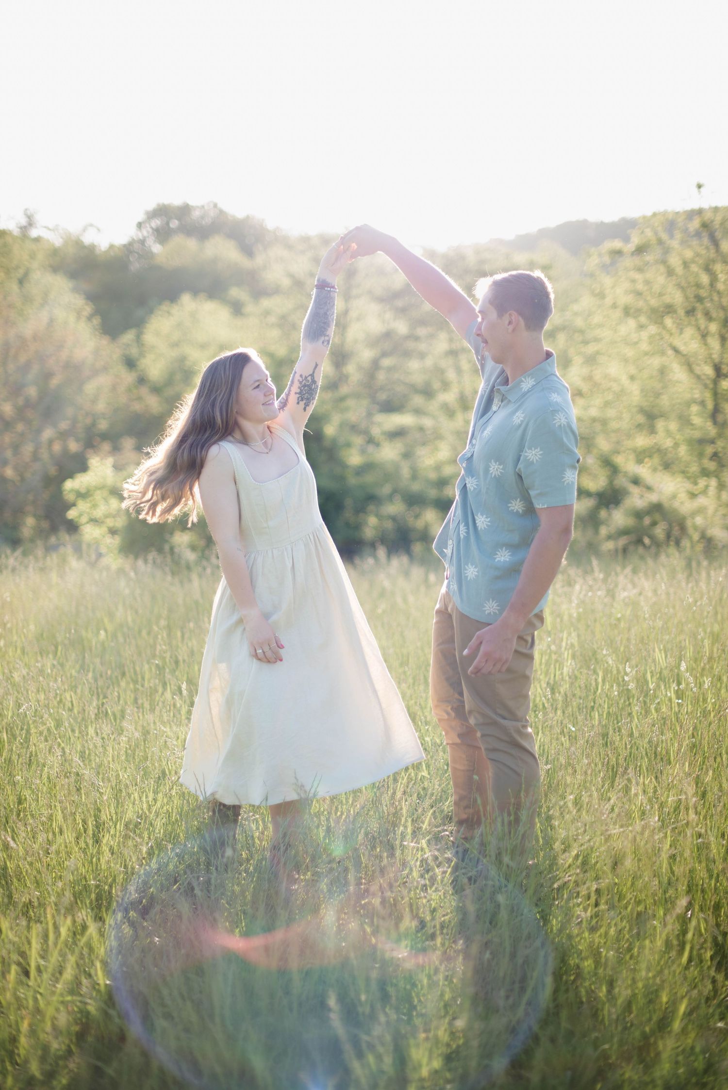 Man spinning girlfriend in a mountain-view field during portrait session