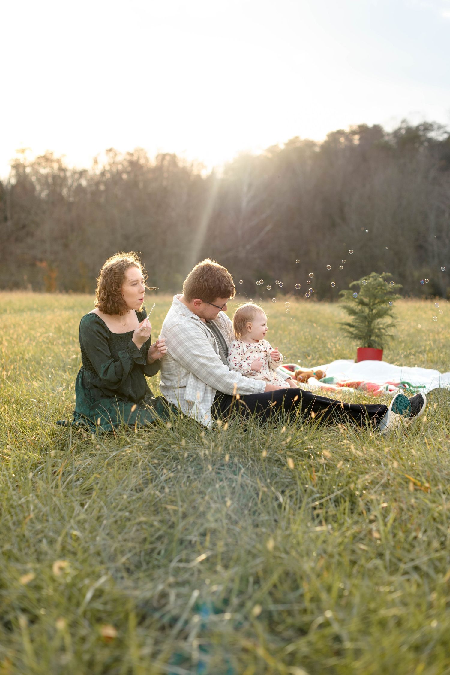 Family sitting in field in the mountains blowing bubbles