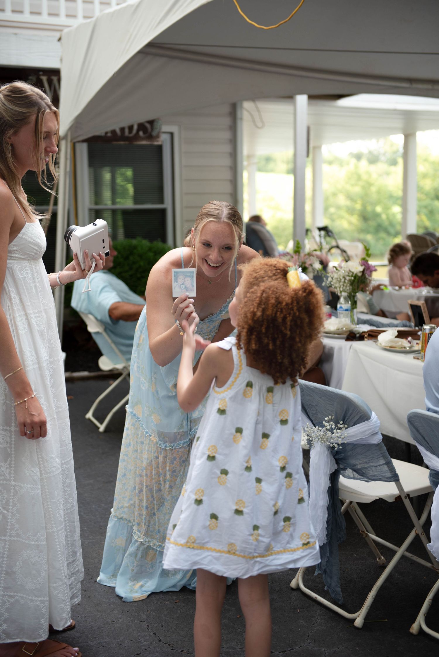Reception of wedding. Bride and maid of honor taking polaroids