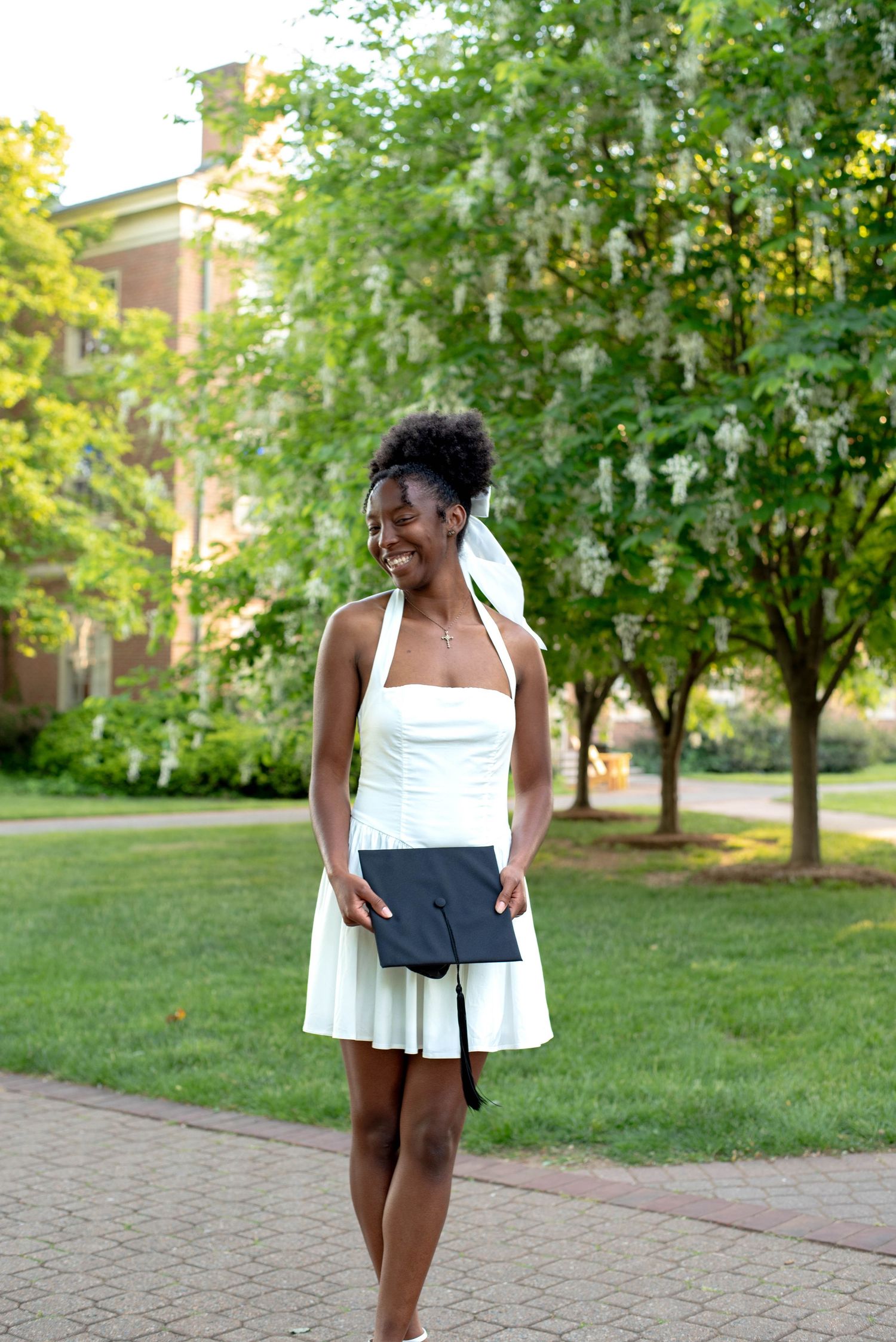Senior graduation photos of girl holding her cap on campus.