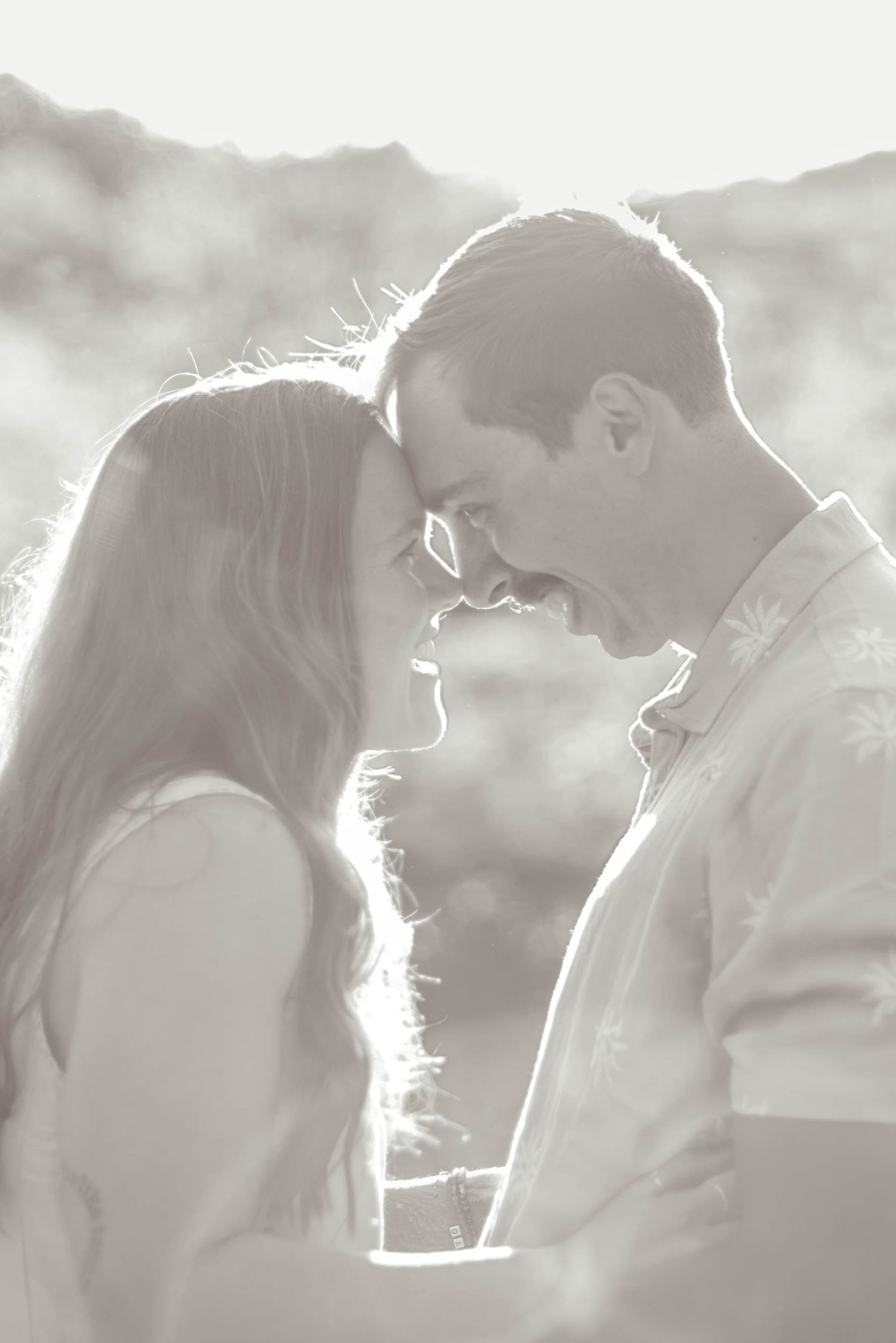 Couple laughing to each other nose-to-nose with mountains in the background
