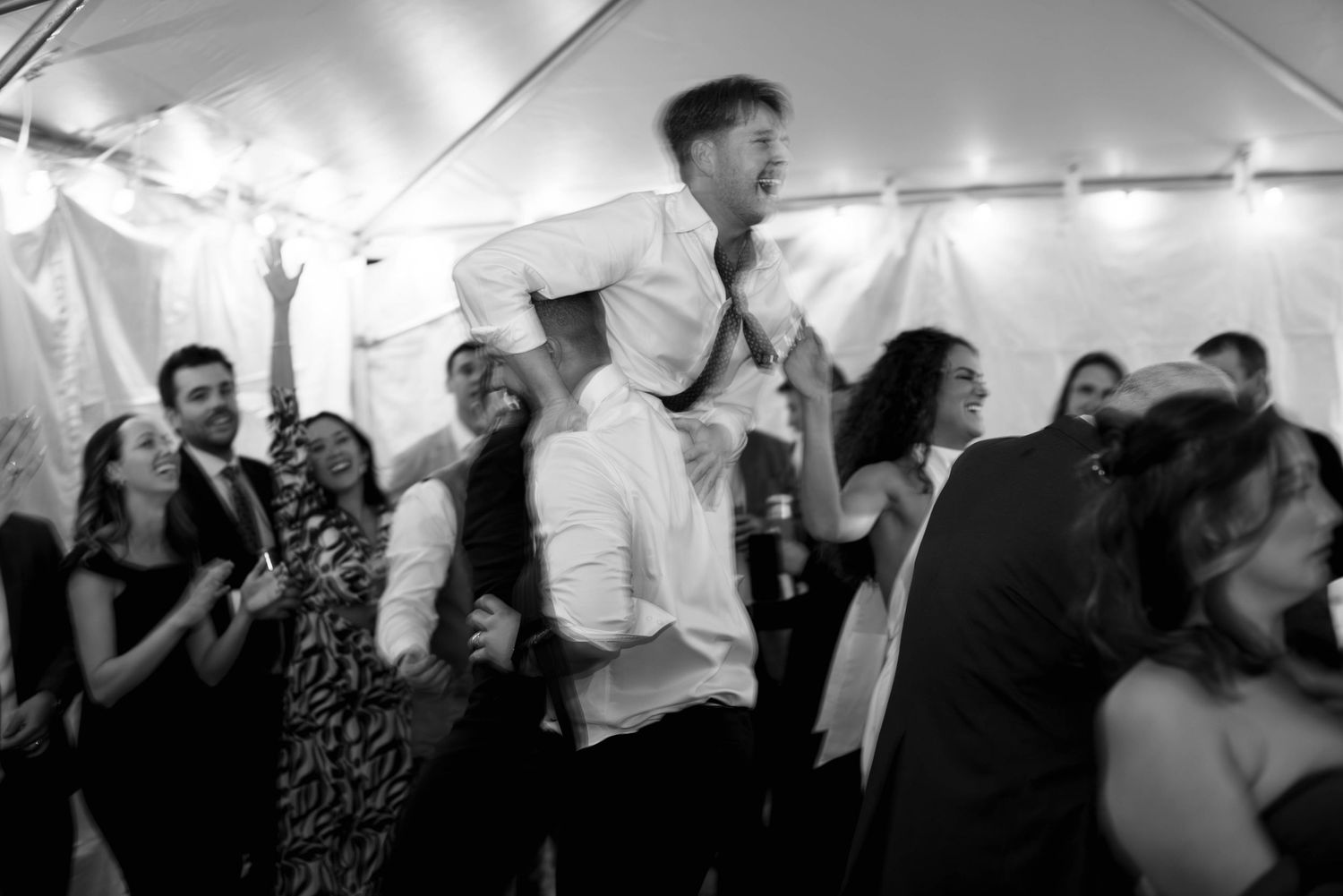 Groom holding a friend on his shoulder during wedding reception