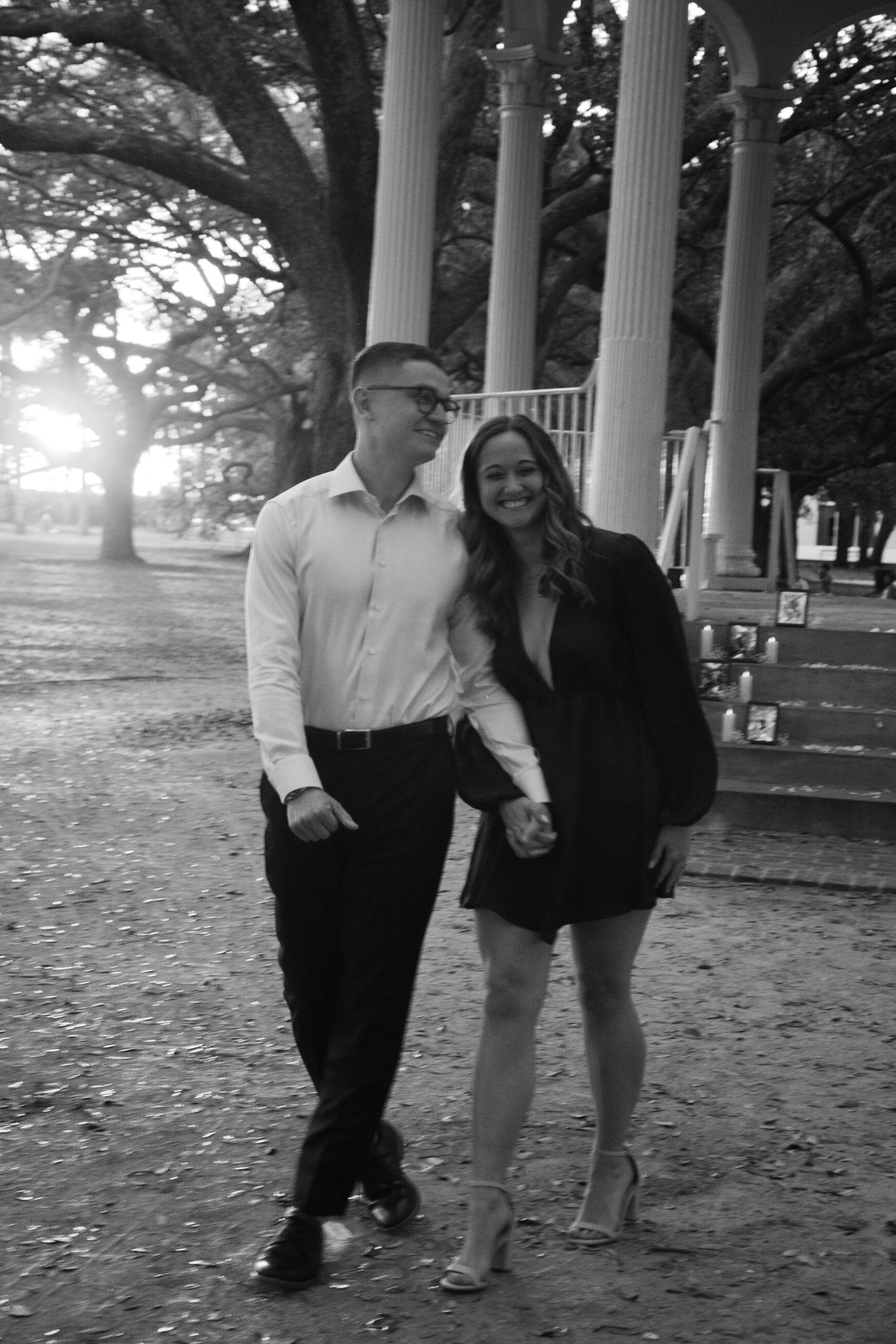 Black and white image of a couple holding hands and laughing after engagement proposal