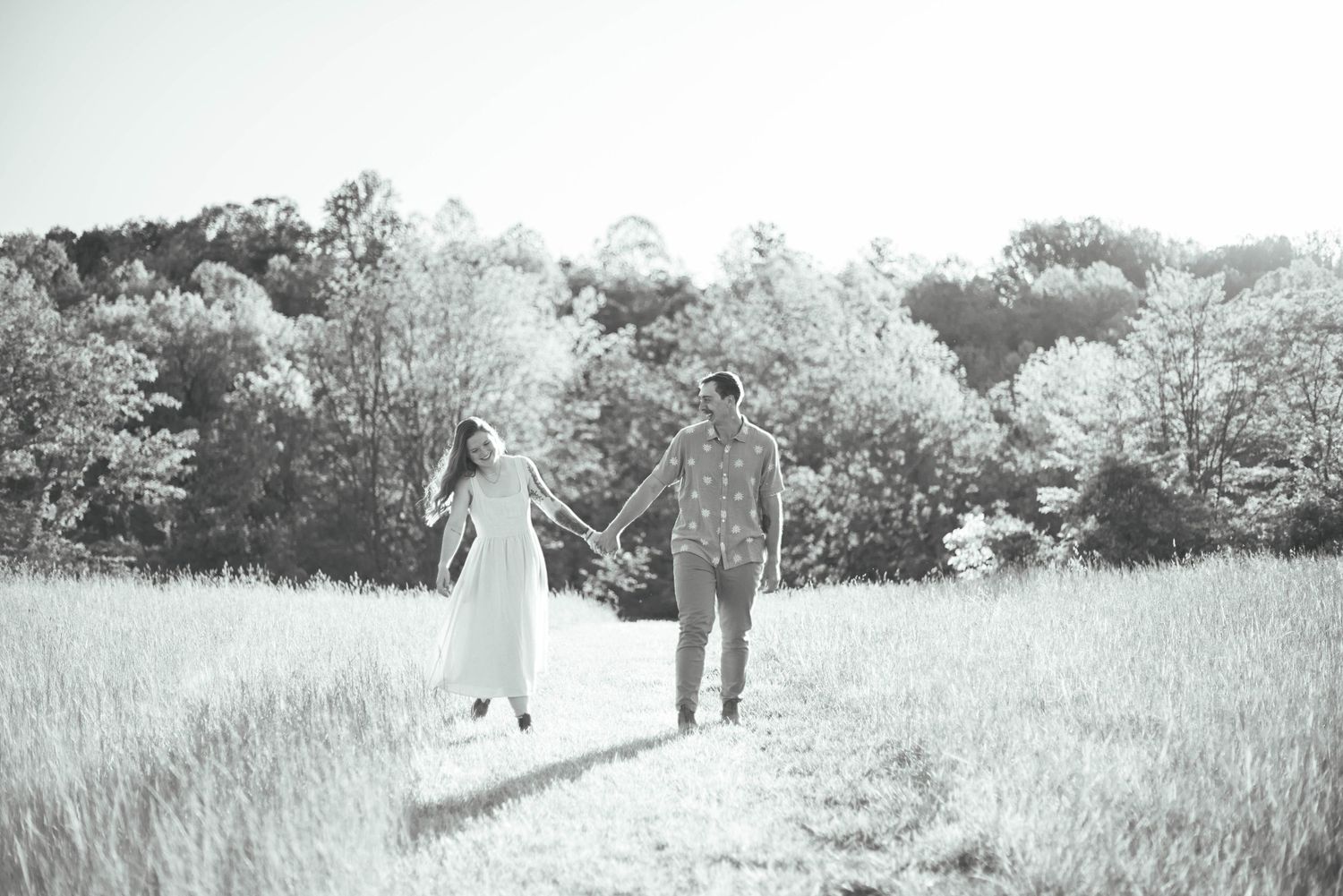 Couple holding hands walking through a field during portrait session