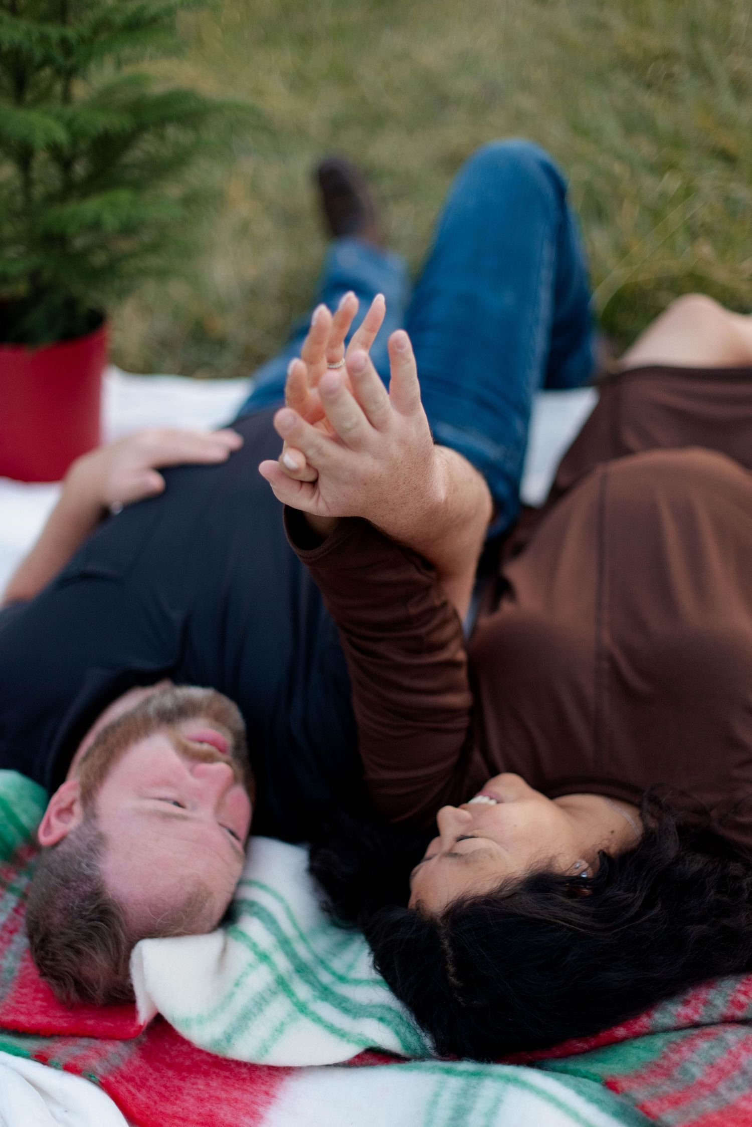 Parents laying on a blanket in a field laughing