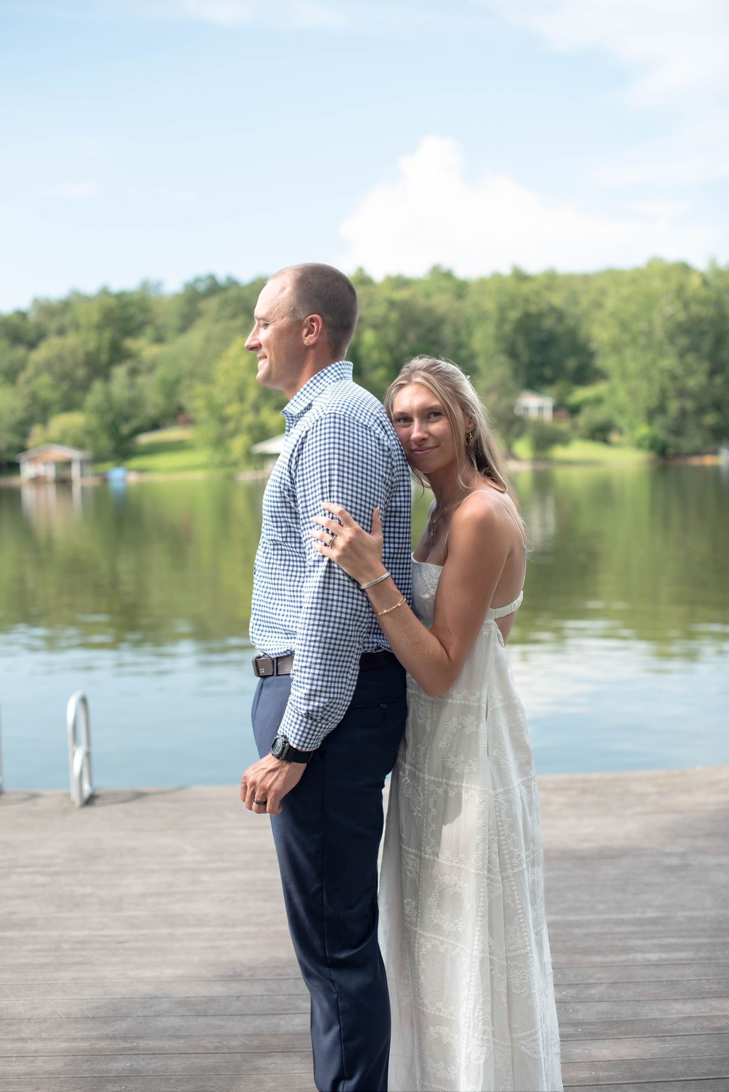 bride and groom standing on dock with lake in background