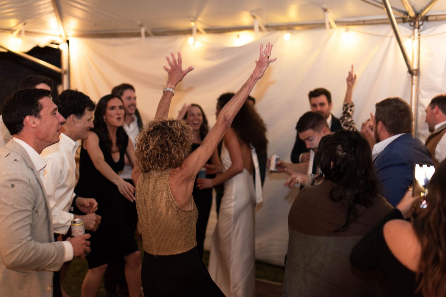 Mother of the bride dancing with arms up on the dance floor during wedding reception