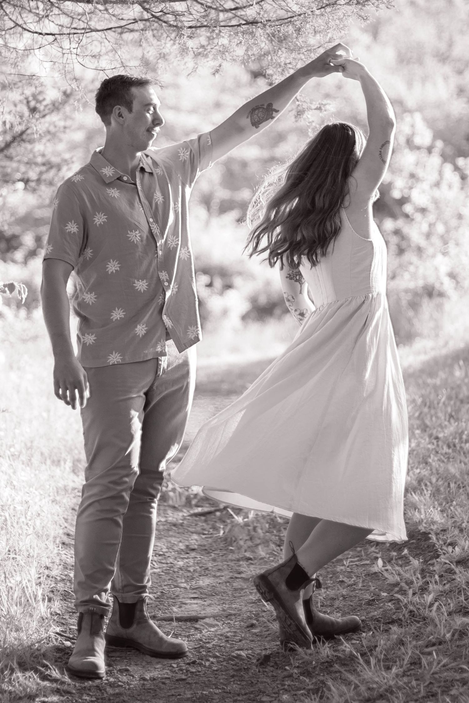 Man spinning girlfriend in a mountain-view field during portrait session