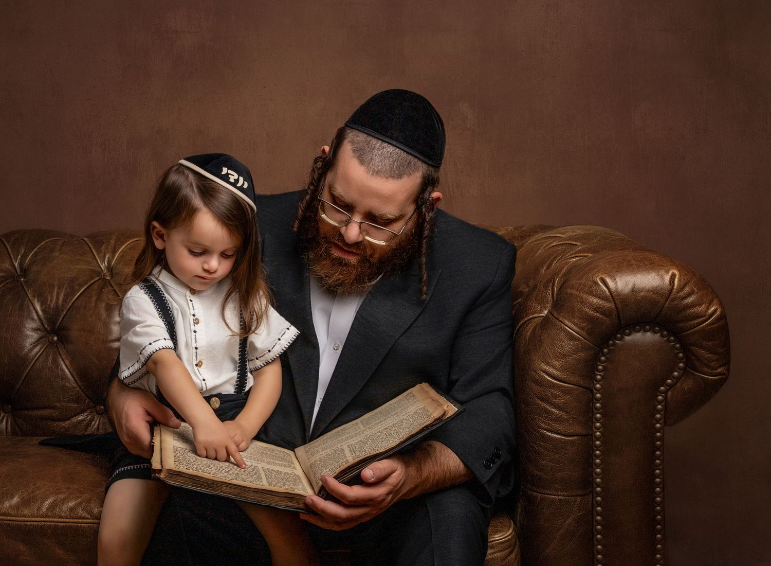 A portrait of a boy and a father reading a book.