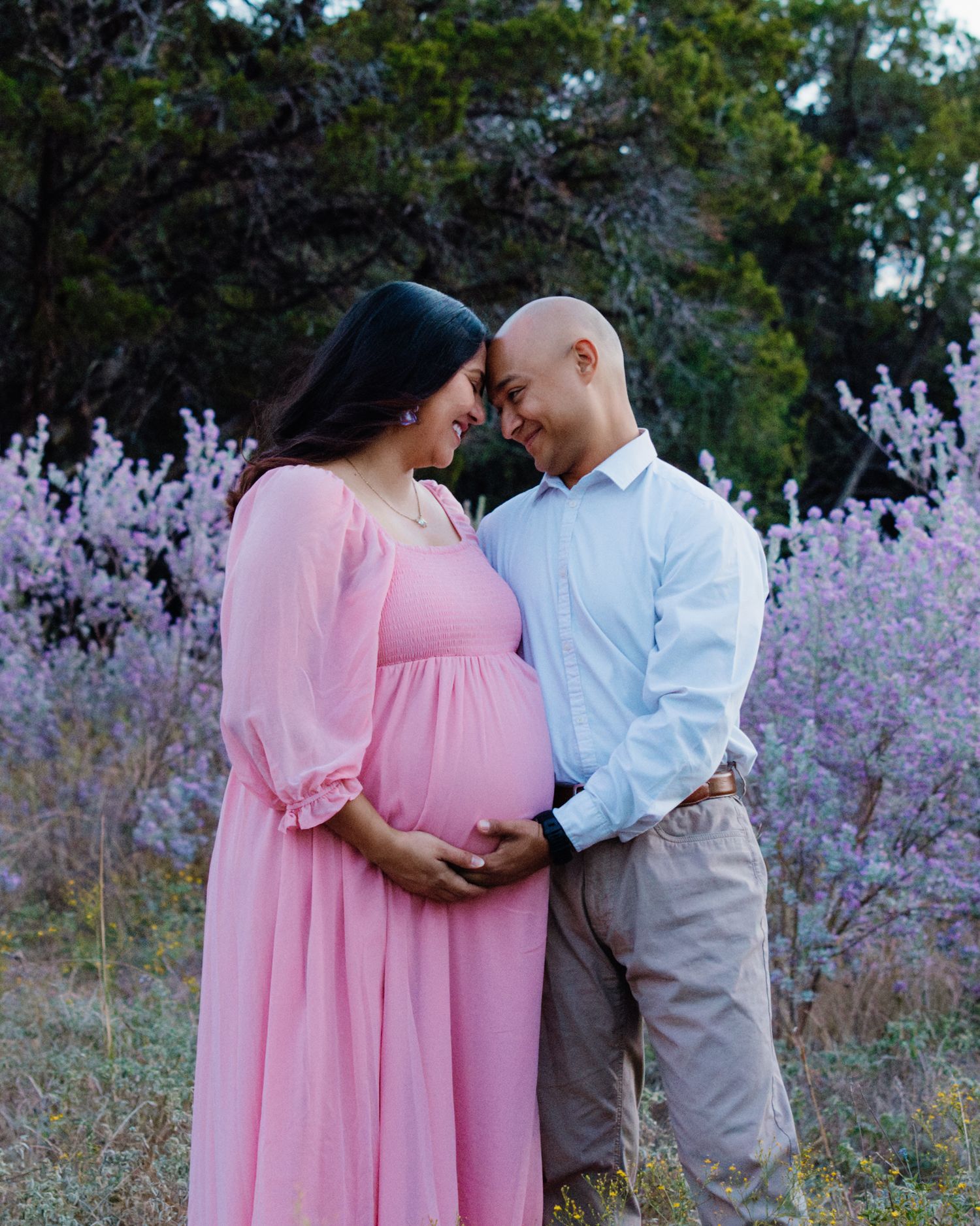 San Antonio Maternity Photography. A tender maternity photo in a field of lavender flowers with a couple in pink and blue outfits.