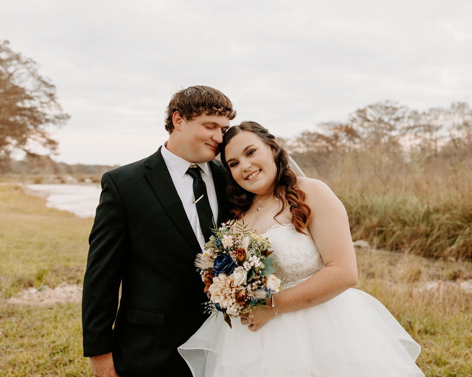 San Antonio Wedding Photography. A wedding couple poses together in formal attire with a natural field backdrop.