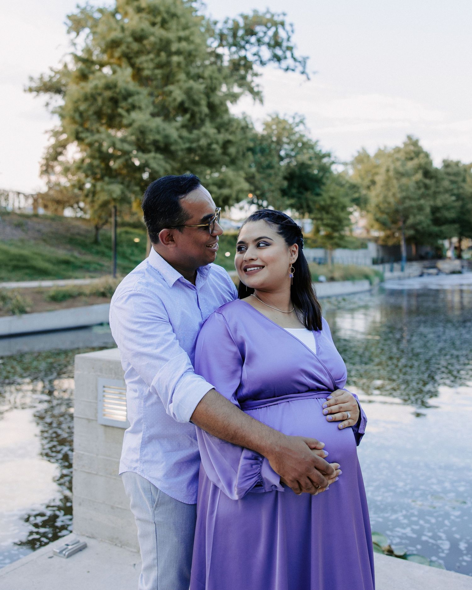 San Antonio Maternity Photography. Expectant couple poses lovingly by a pond during sunset maternity photoshoot.