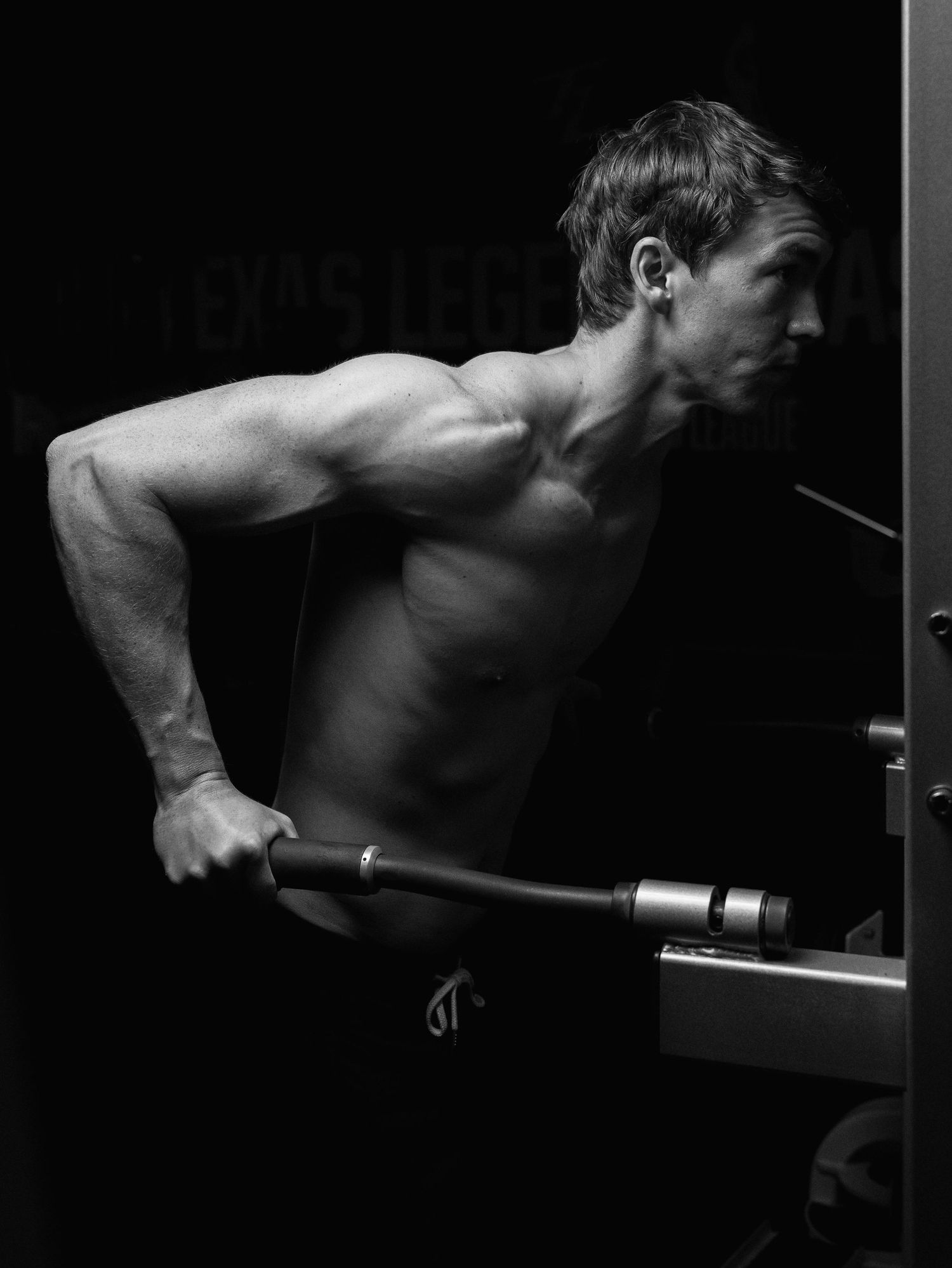 A sequence of black and white photos showing a muscular back performing dips exercise on parallel bars.