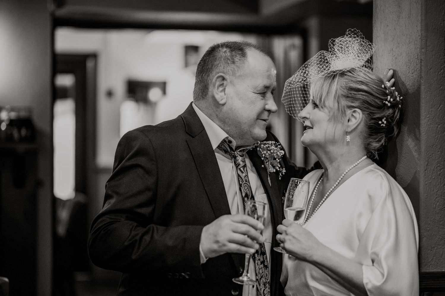 Intimate black and white photo of a couple sharing champagne during their wedding celebration.