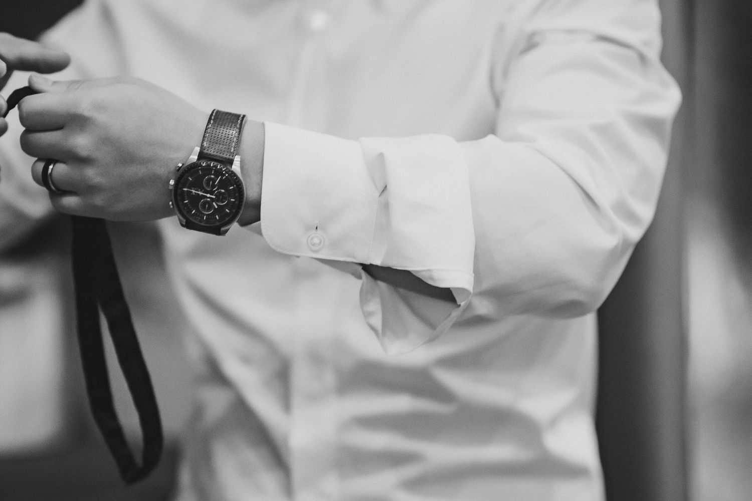 Timeless black and white editorial edit of the groom getting ready, with a focus on smaller details like his watch.
