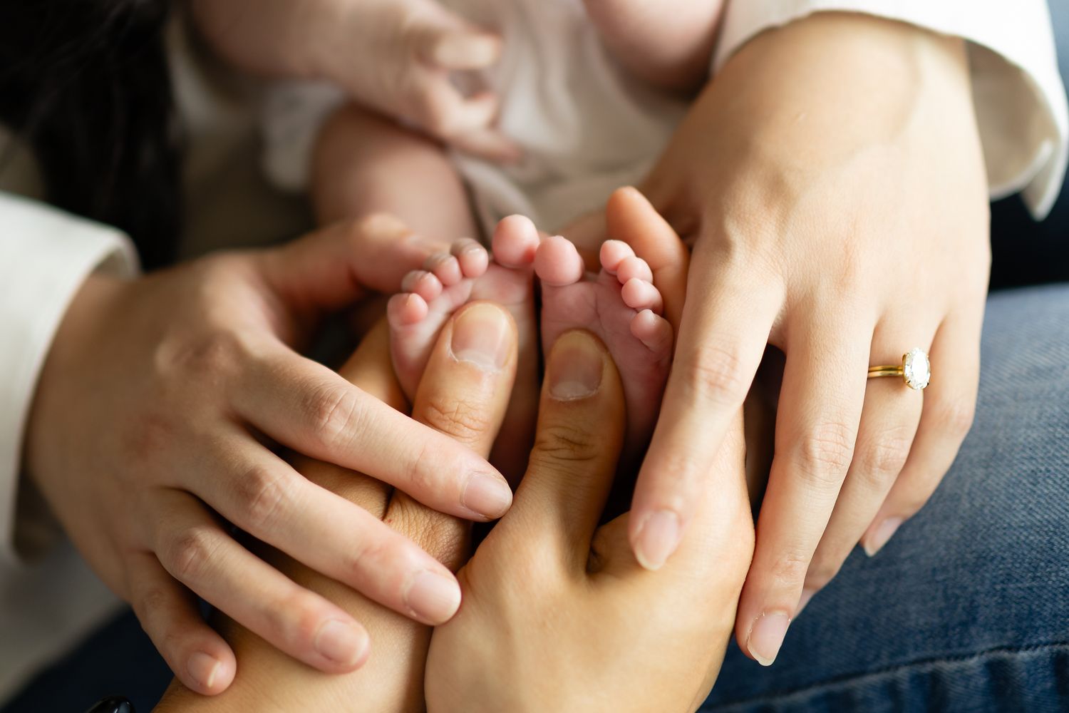 New mom and dad hold their newborn daughters tiny feet during an in-home lifestyle newborn session near Tacoma.