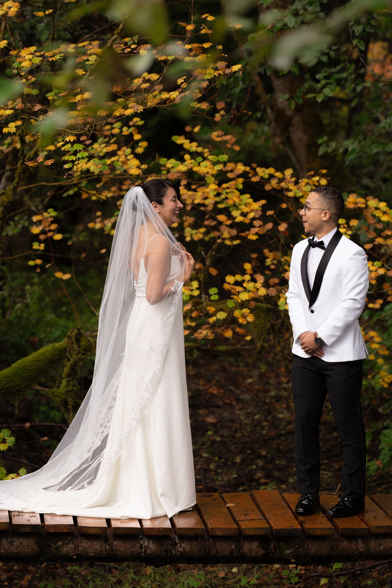 The groom turns to view his bride for the first time in her wedding attire. Their expressions are joyful with excitement for their ceremony.