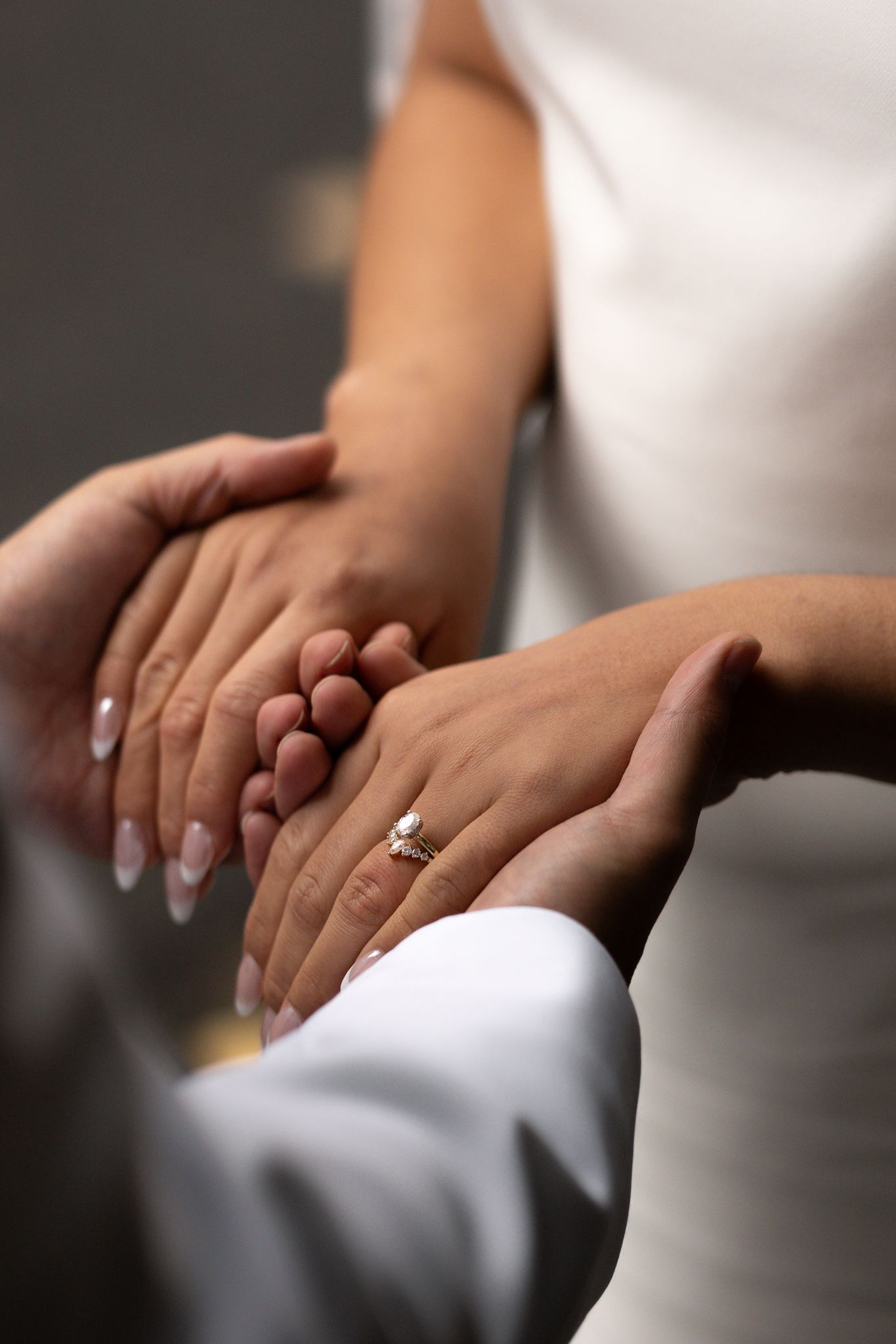 Creamy contrasted edit of a brides hands in her grooms, with a sharp focus on her wedding rings.