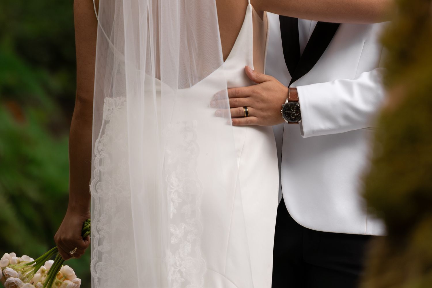 Cropped perspective of the Pacific Northwest bride and groom with focus on details like his wedding ring, watch and her veil draped back,