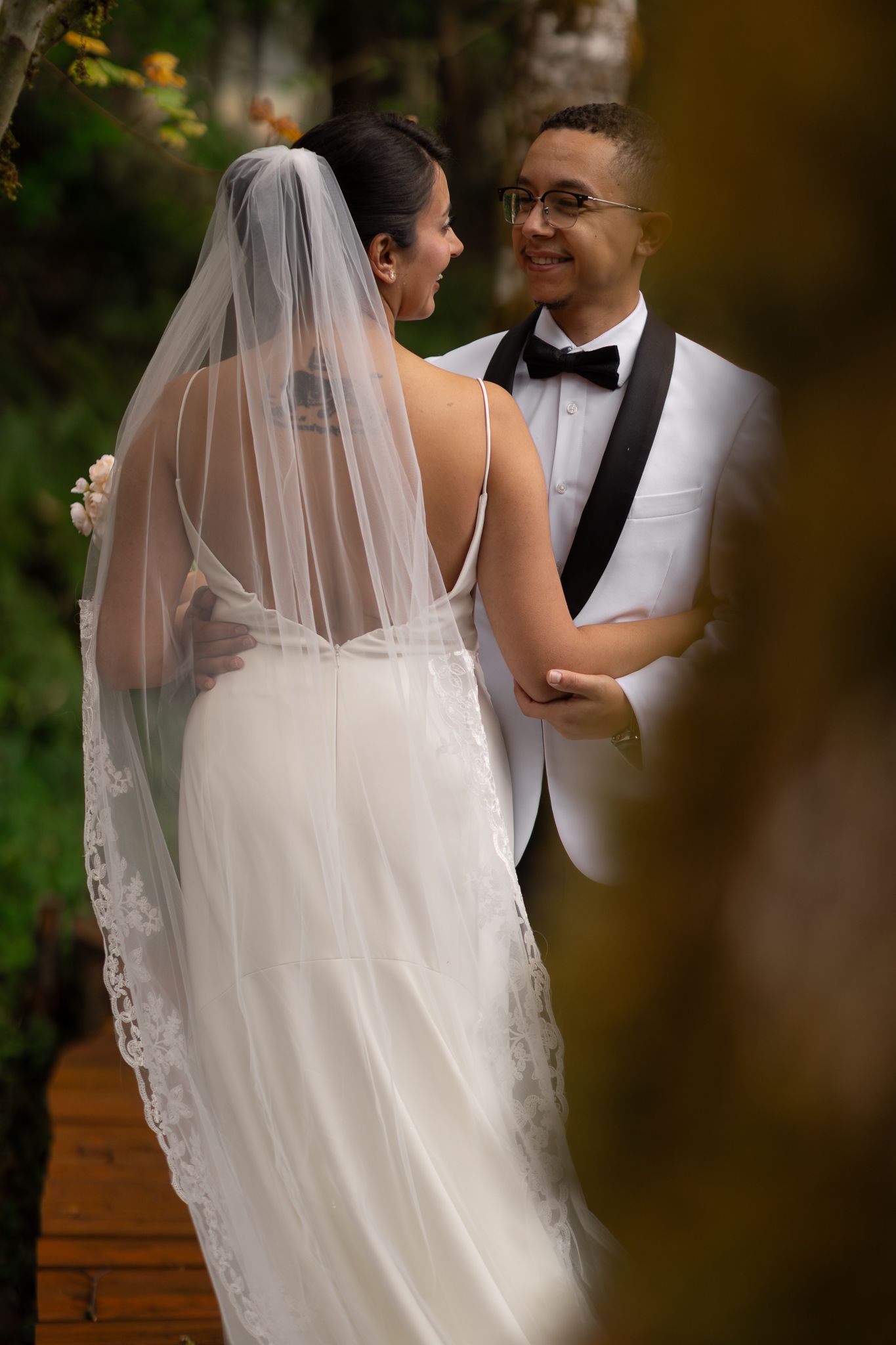 Photographers perspective of a bride and groom through a mossy tree near Mount Rainier.