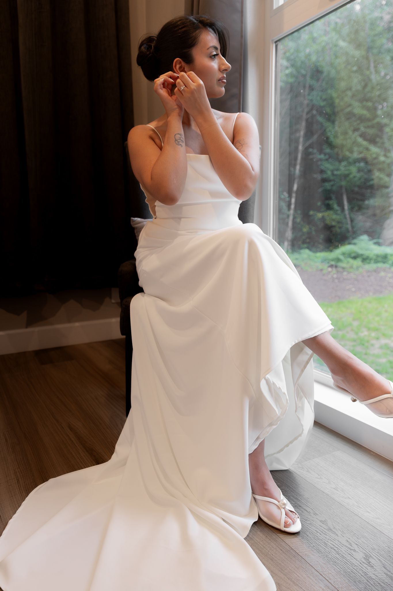 A bride puts on her earrings while she prepares for first looks with her fiance at their bnb before their micro wedding near Mount Rainier.