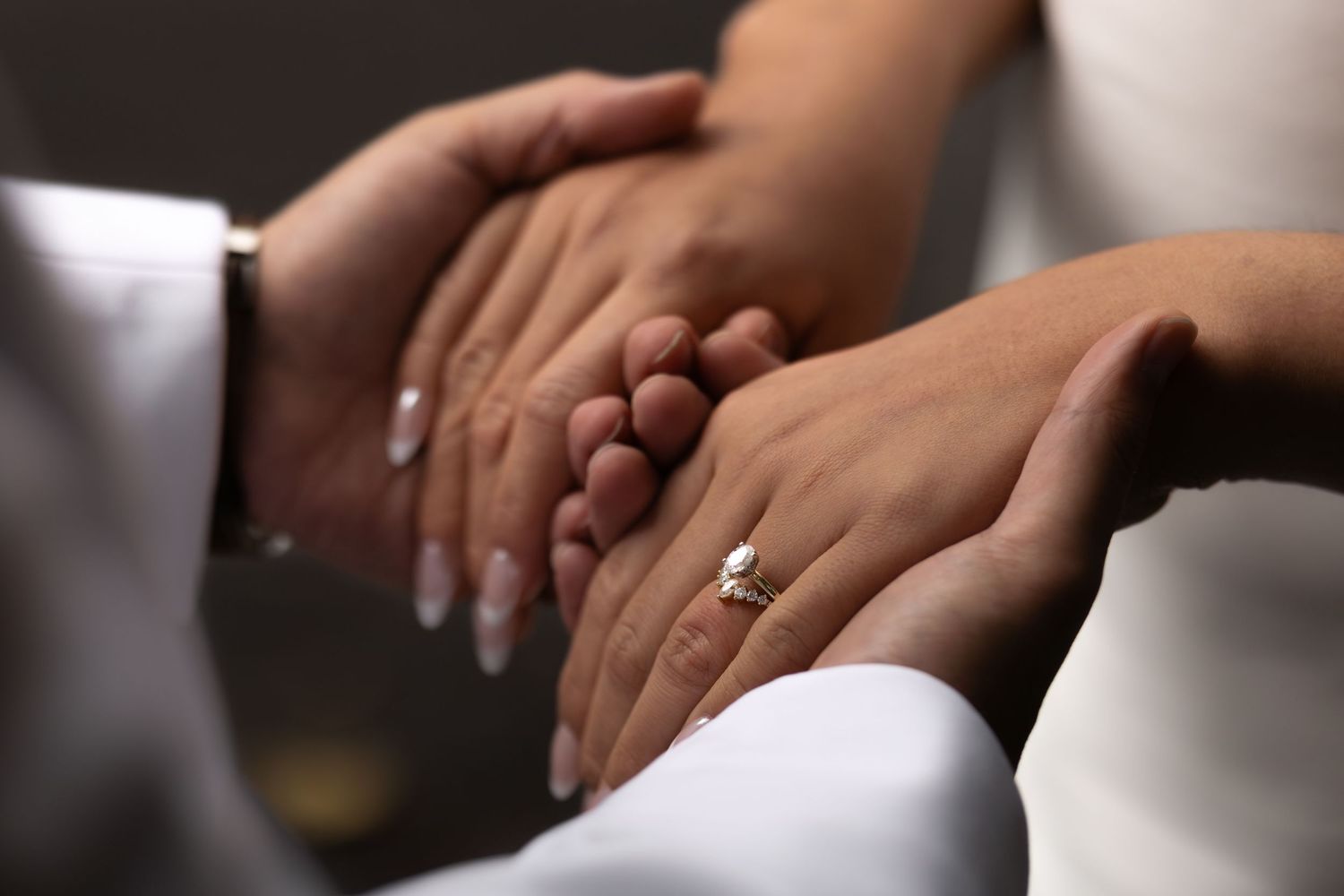 Groom holds his new wife's hands, displaying her wedding and engagement rings in a high contrast photo during their Mount Rainier elopement.