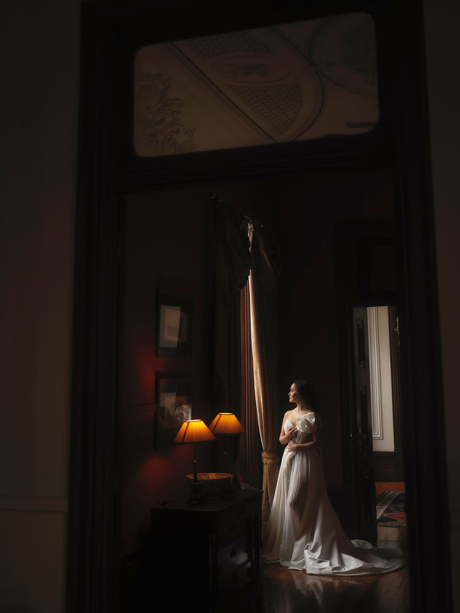 A sequence of moody photos shows a figure in white standing in a dimly lit room with dramatic lighting and shadows.