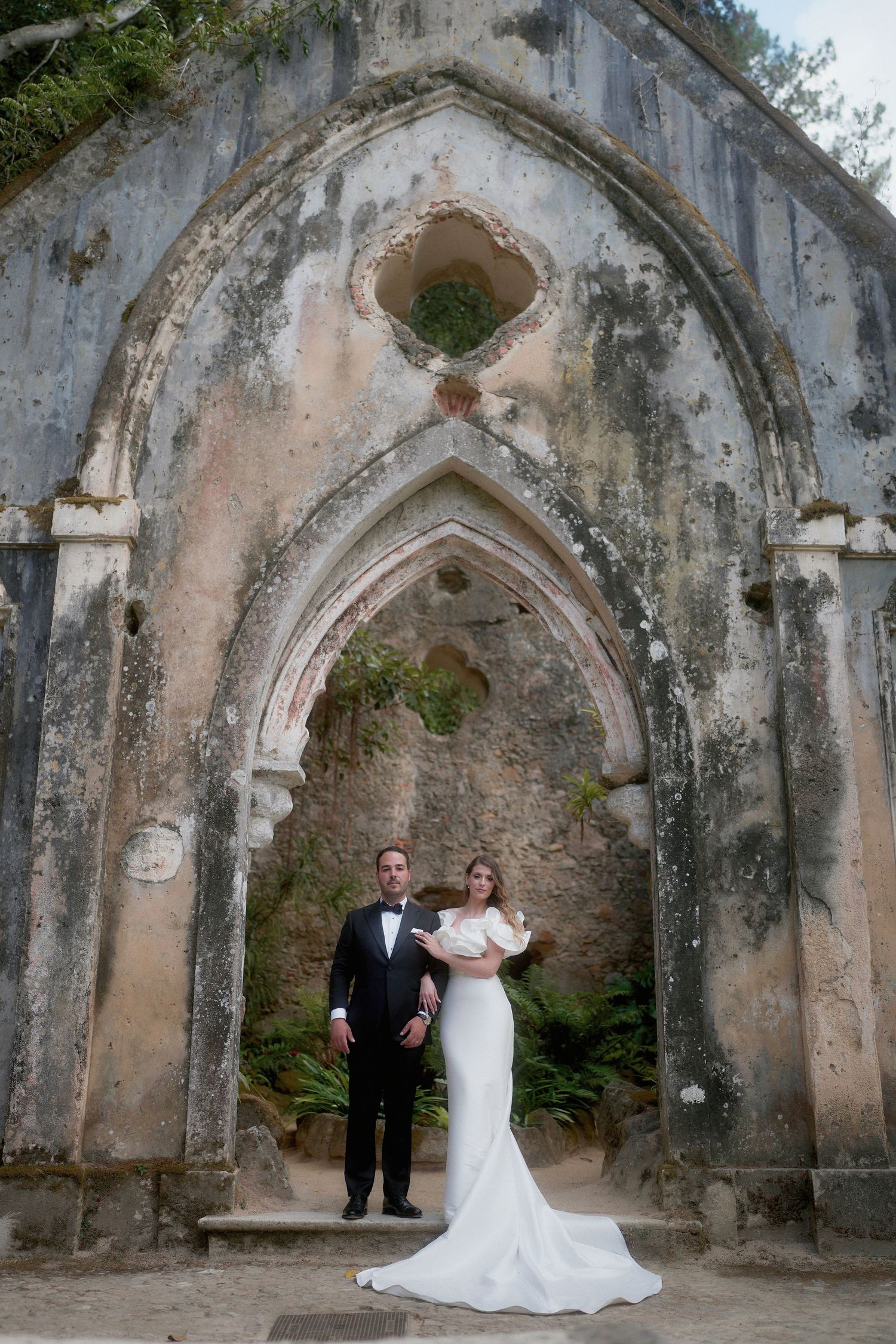 Ancient stone archway with weathered walls and gothic architectural details in a historic ruins setting.