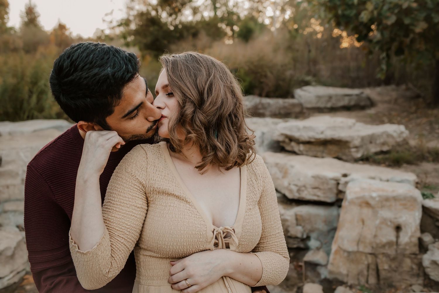 Mom and dad kissing during maternity session in Forest Park.