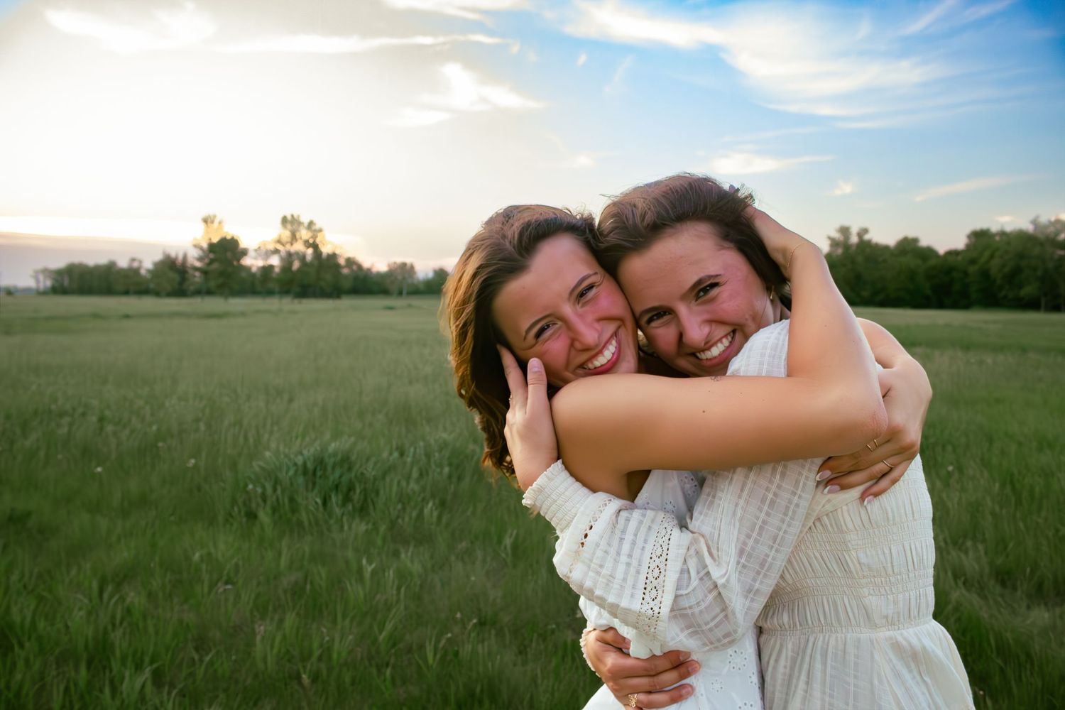 two female friends posing in a field at sunset