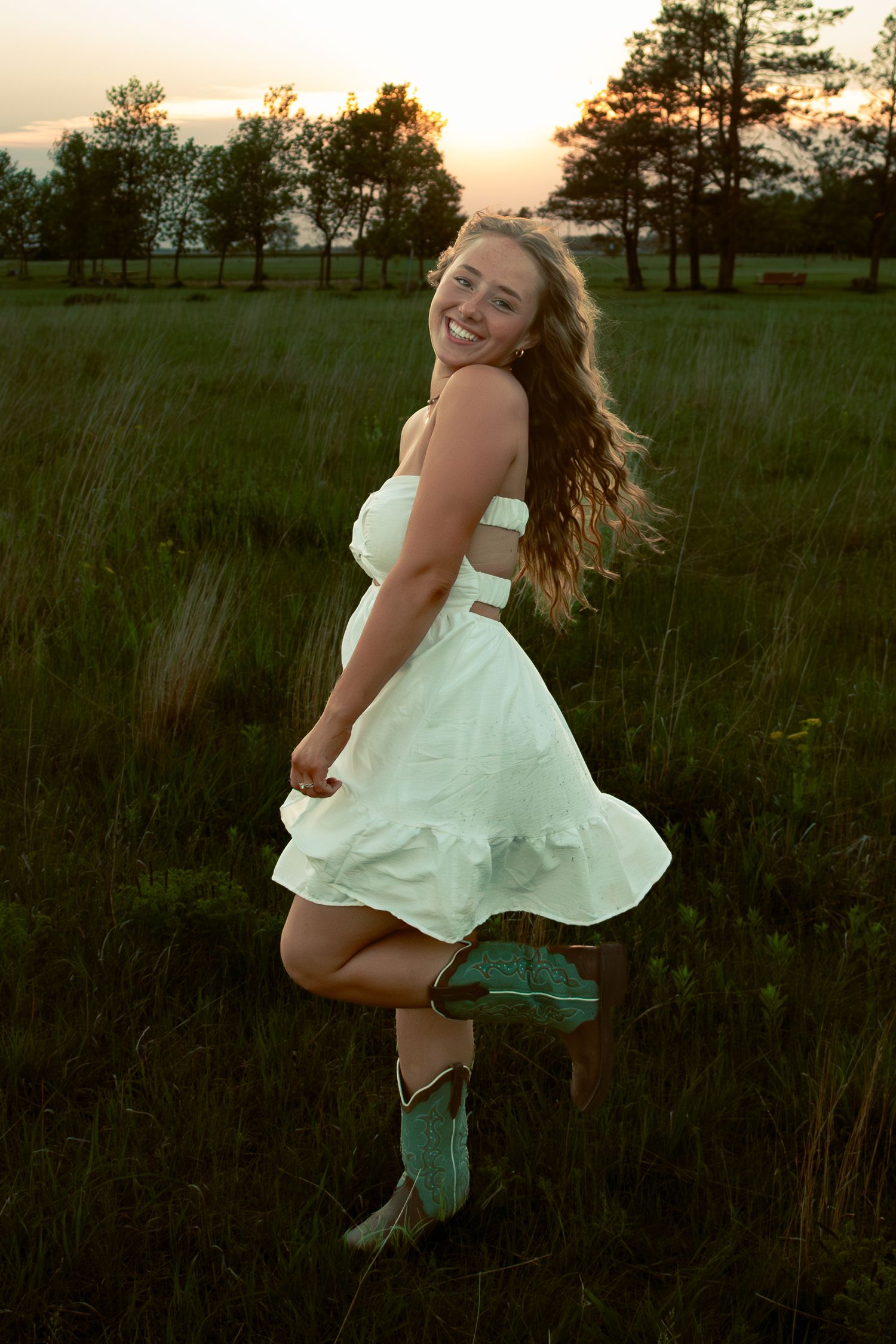 young woman posing in a field at sunset