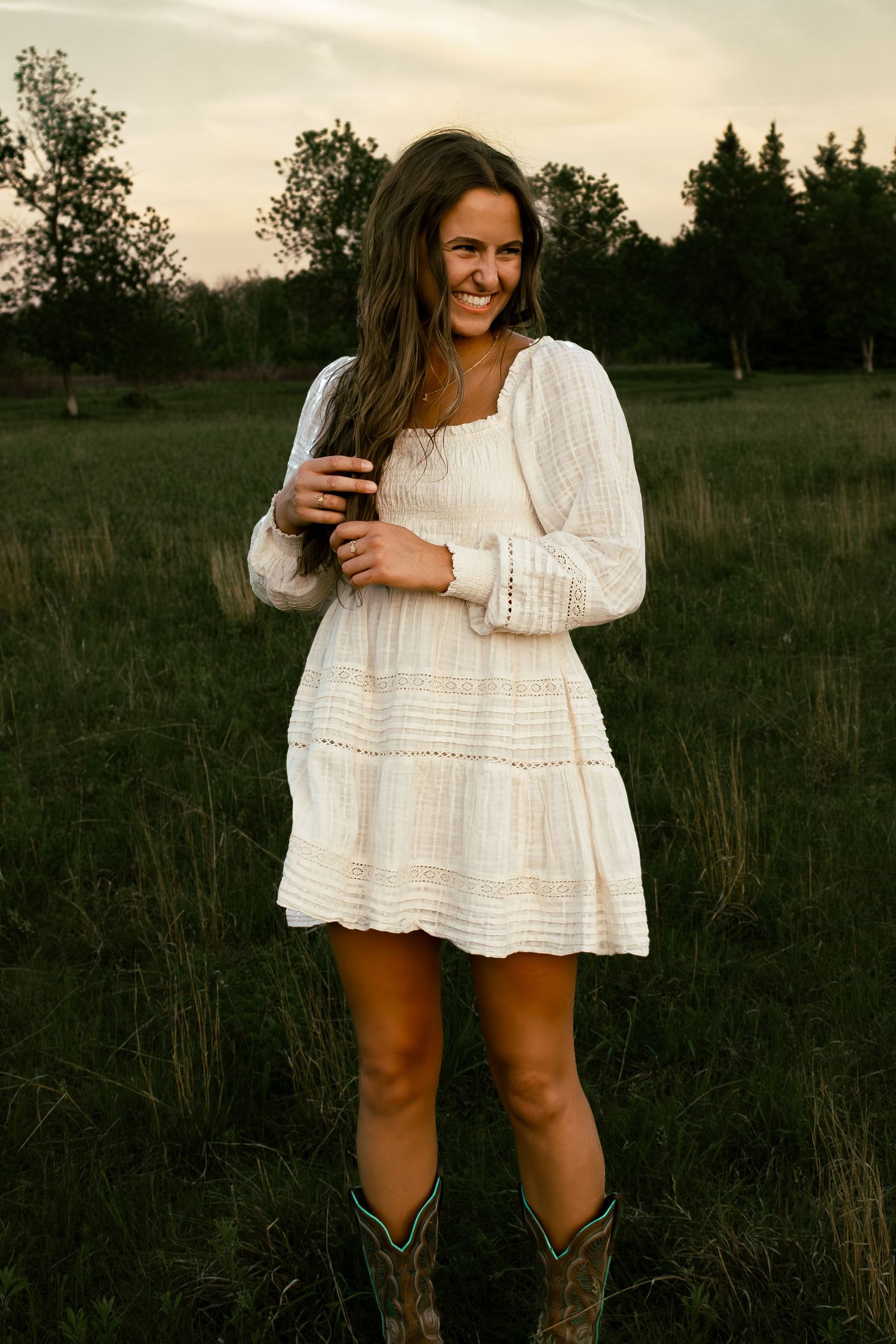 young woman posing in a field at sunset