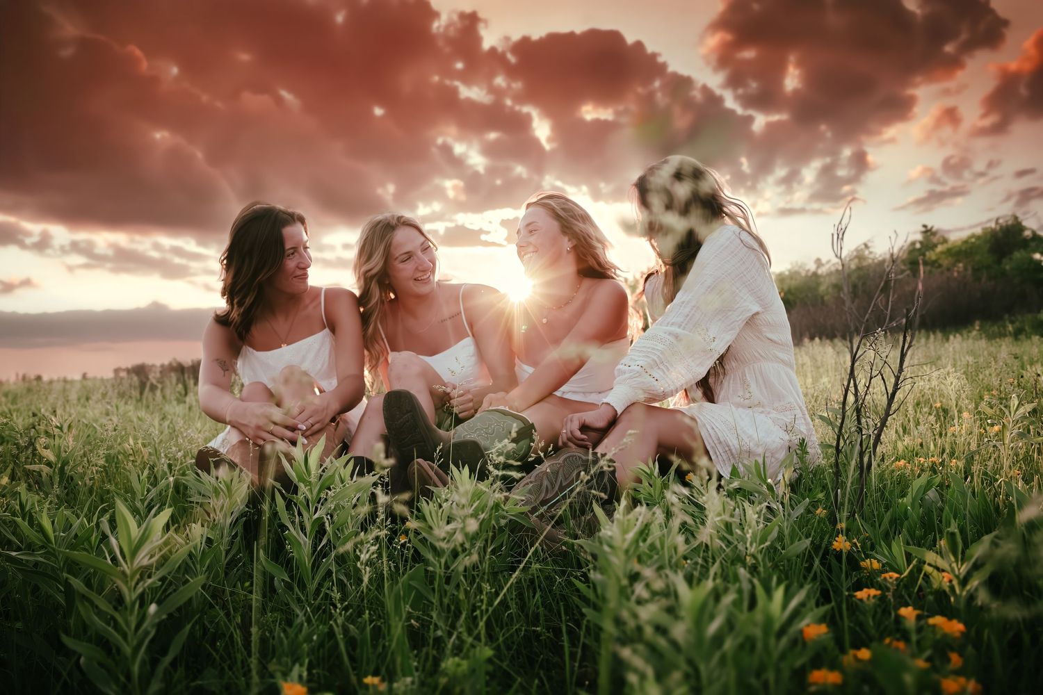 four female friends posing in a field at sunset