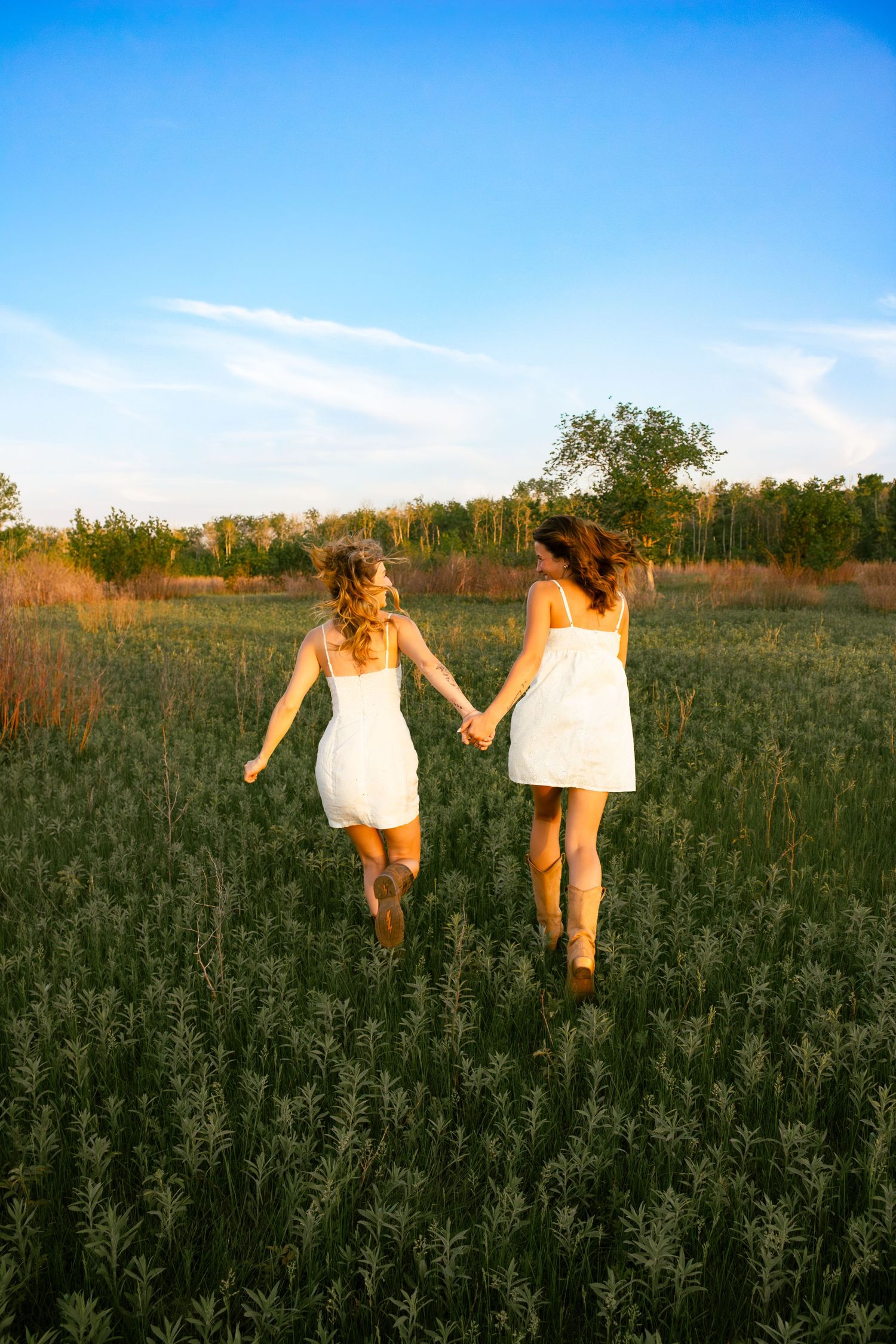 two female friends posing in a field at sunset