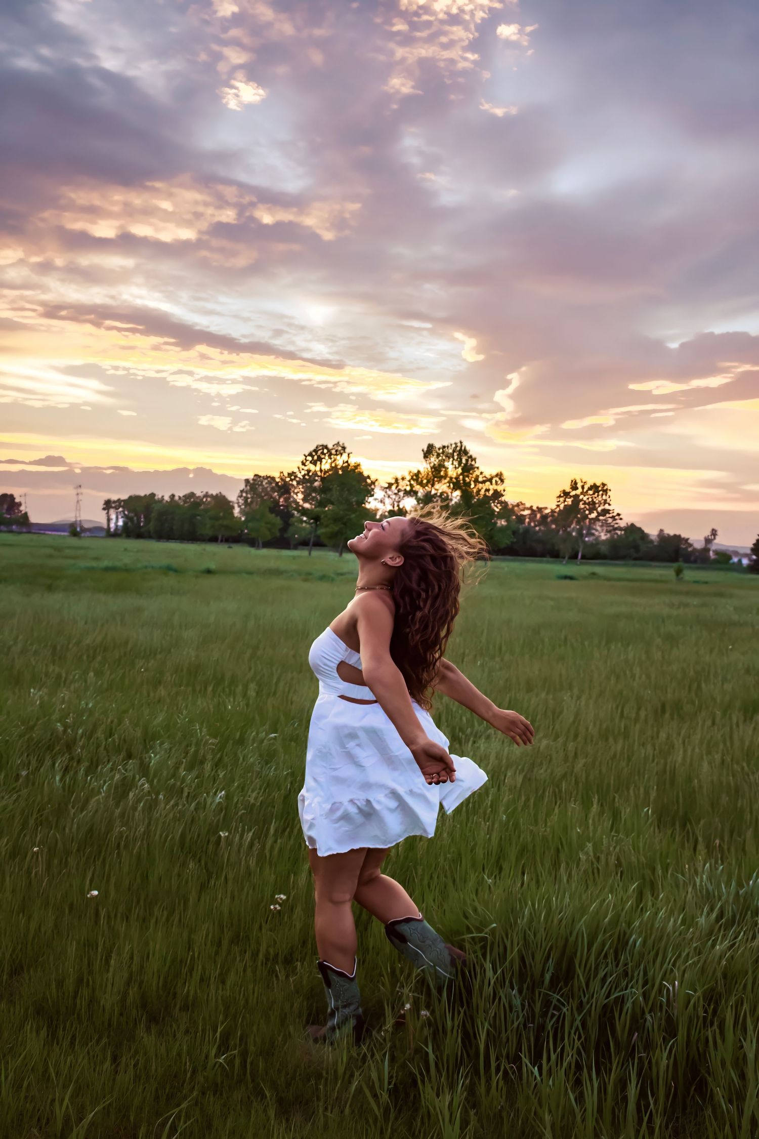young woman posing in a field at sunset