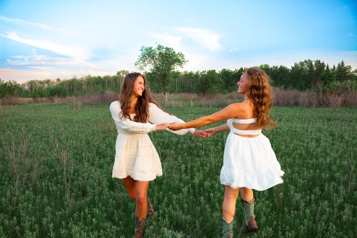 two female friends posing in a field at sunset